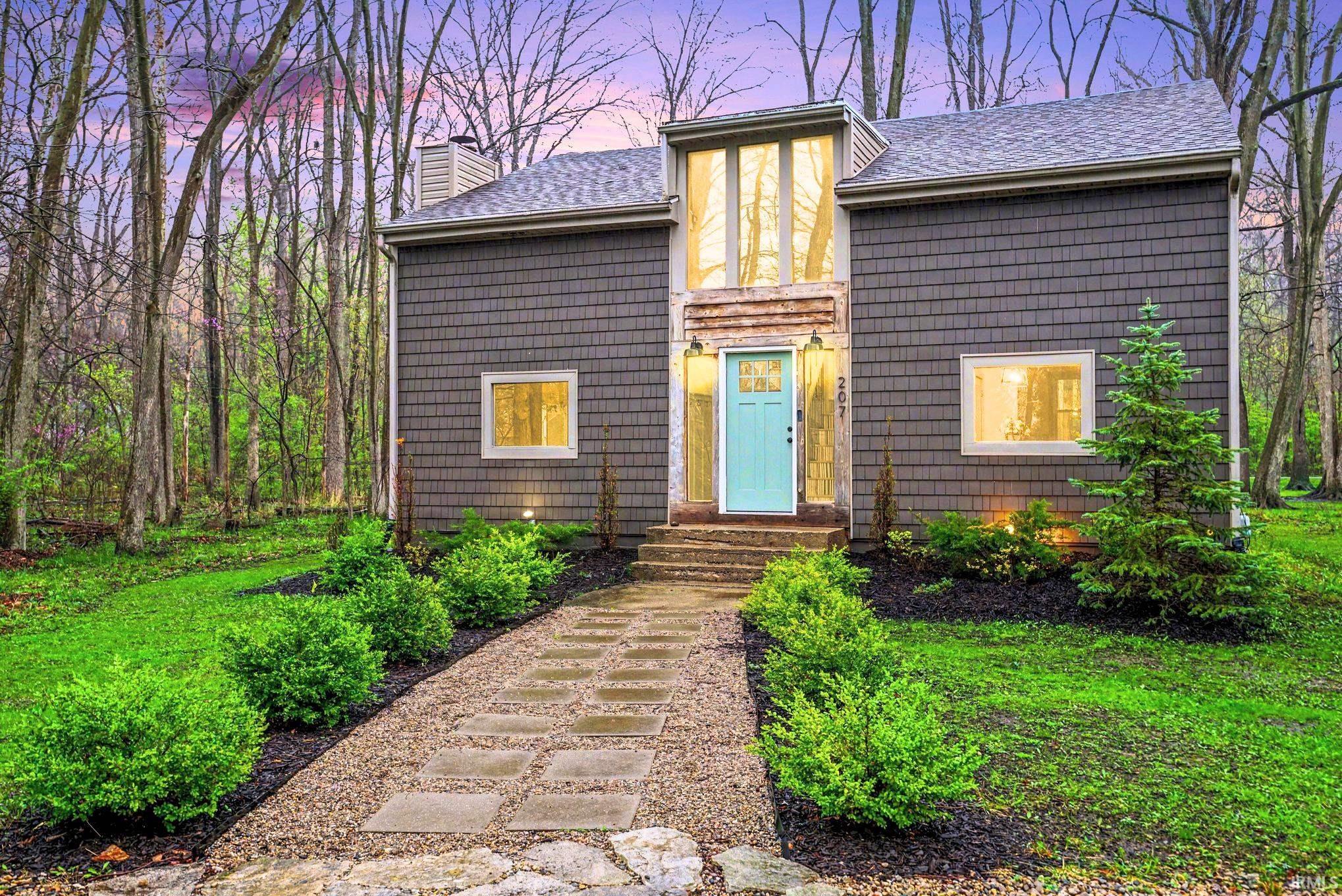 Image 0: View of front of home with a chimney and a shingled roof, Front of home with proffesional landscaping