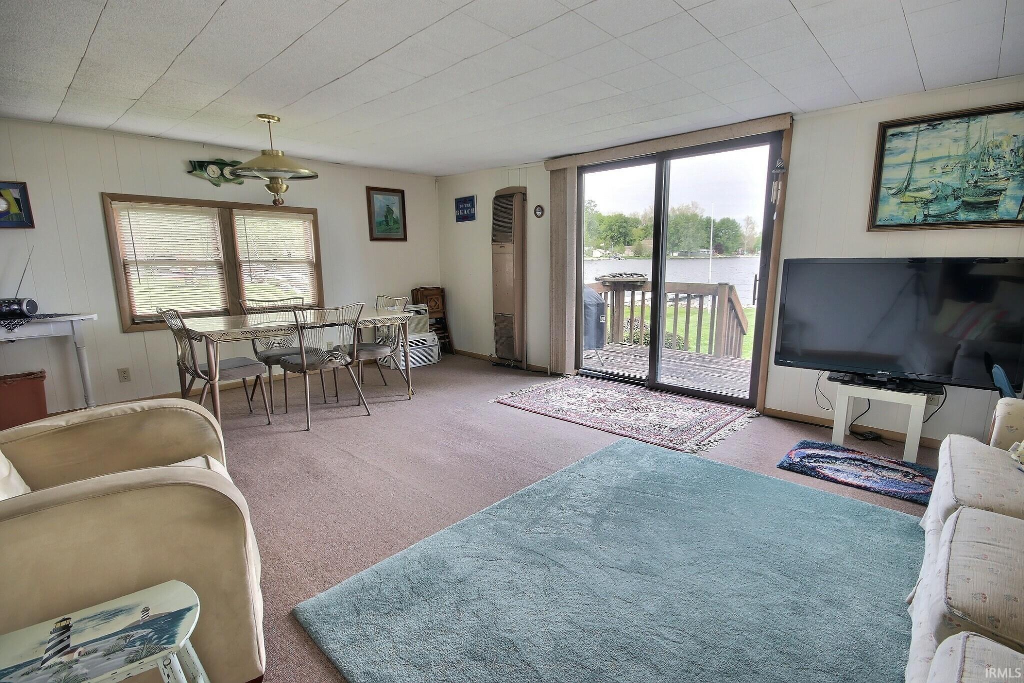 Image 3: Carpeted living area featuring a sliding glass door providing access to an exterior deck overlooking a body of water, Living Room Image 3: Carpeted living area featuring a sliding glass door providing access to an exterior deck overlooking a body of water, Living Room