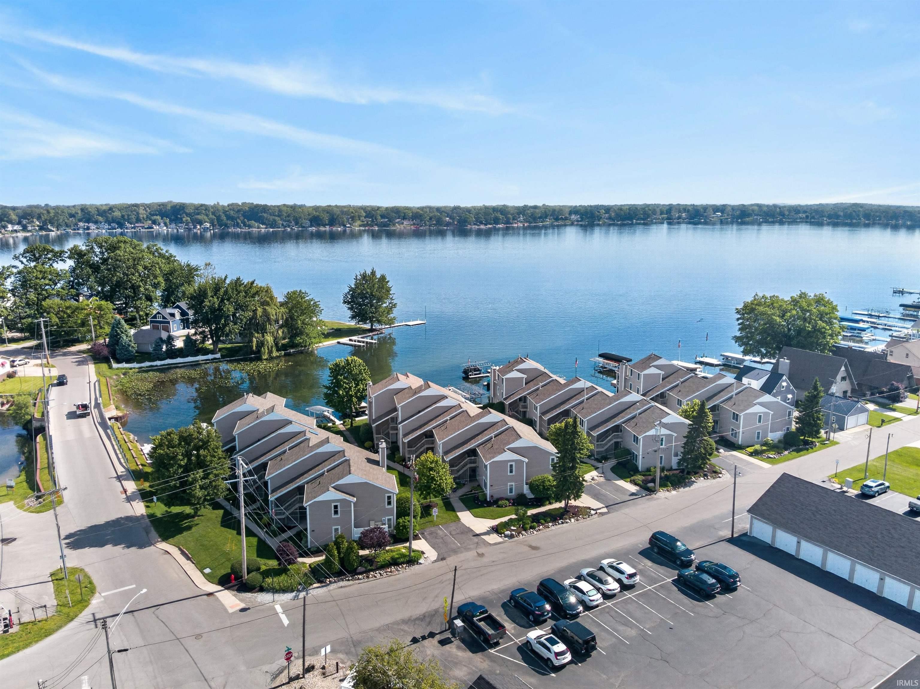 Image 2: Waterfront condominium complex featuring a dock system, ample surface parking, and a separate garage structure, Aerial View