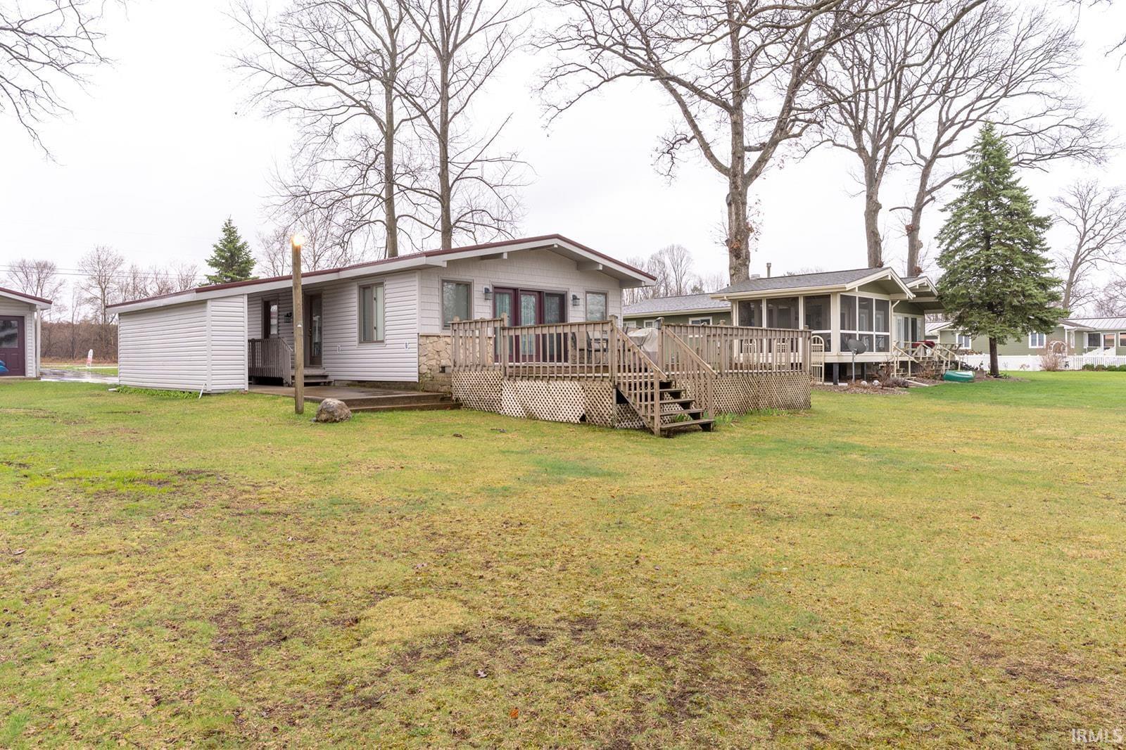 Image 1: Front (Lakeside) of property featuring a wooden deck, a lawn, Front of Structure