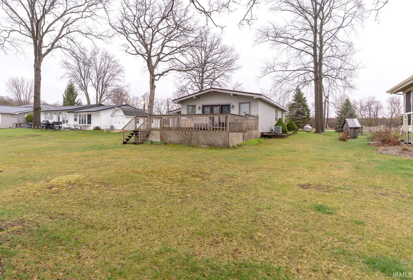Image 2: View of green lawn with a wooden deck and a storage unit, Front of Structure (Lakeside)