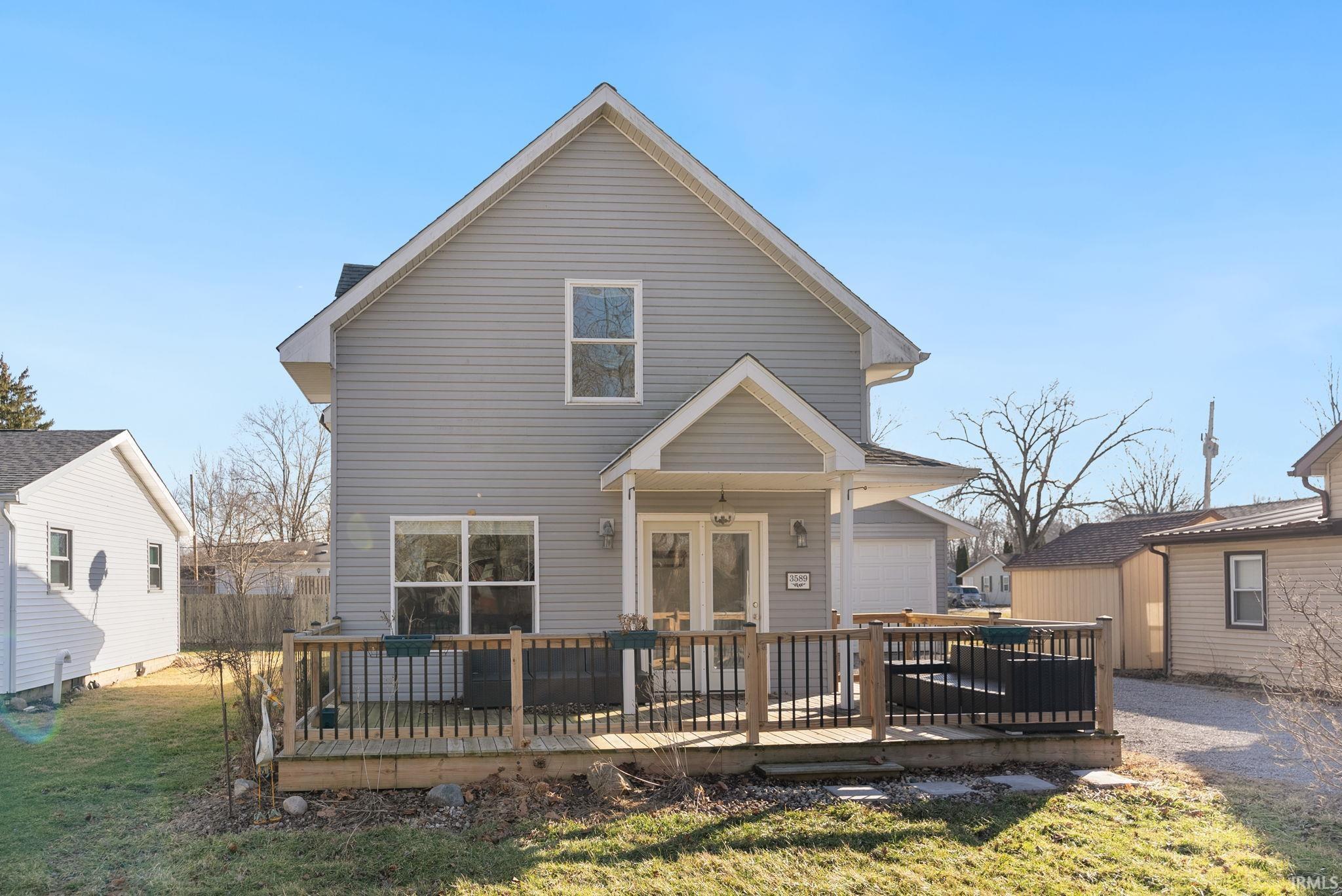 Image 1: Rear view of house with a wooden deck, a lawn, and a garage, Back Of Structure