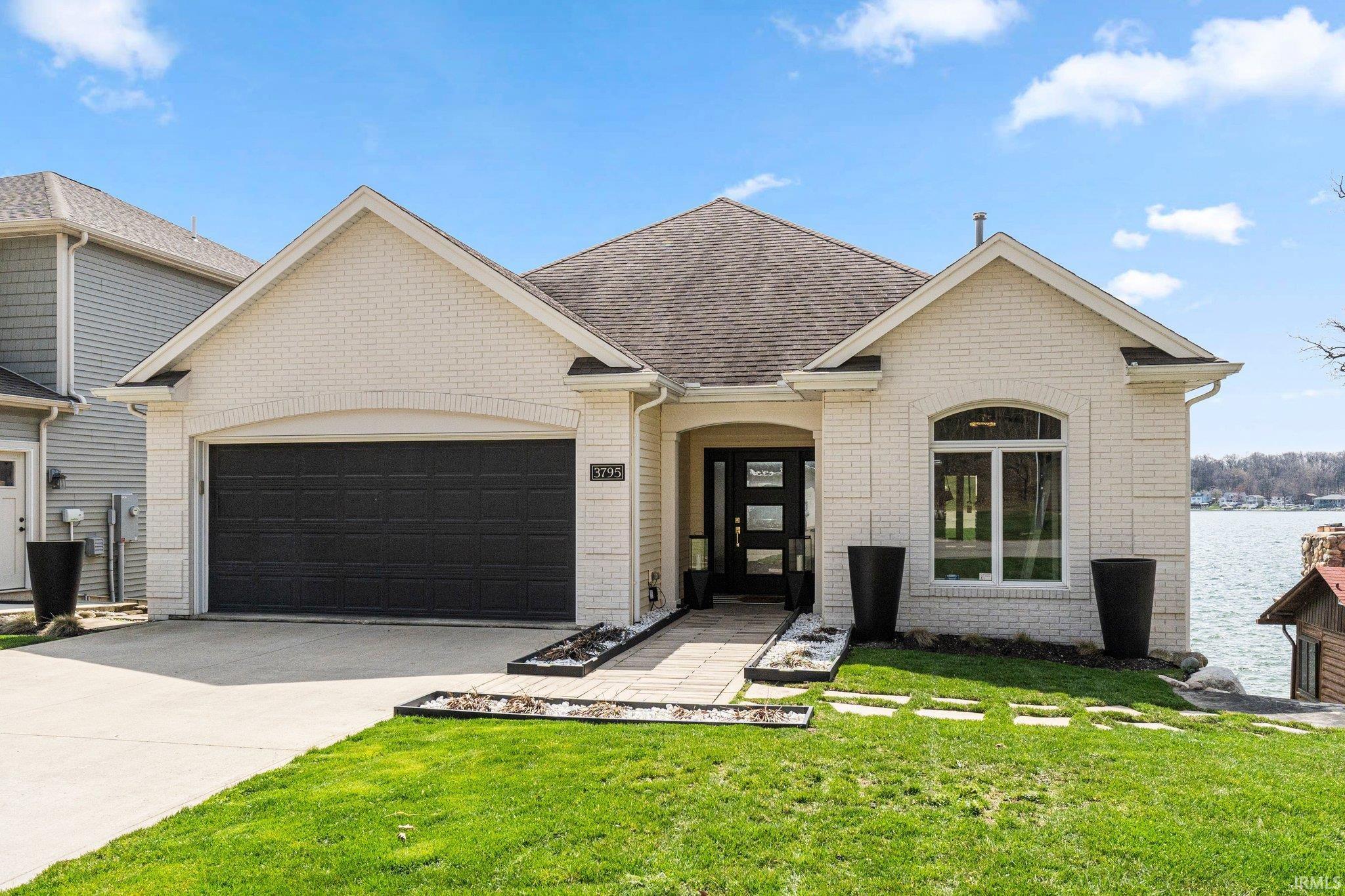 Image 0: View of front facade featuring a garage, a front yard, driveway, brick siding, and a shingled roof, Front Of Structure