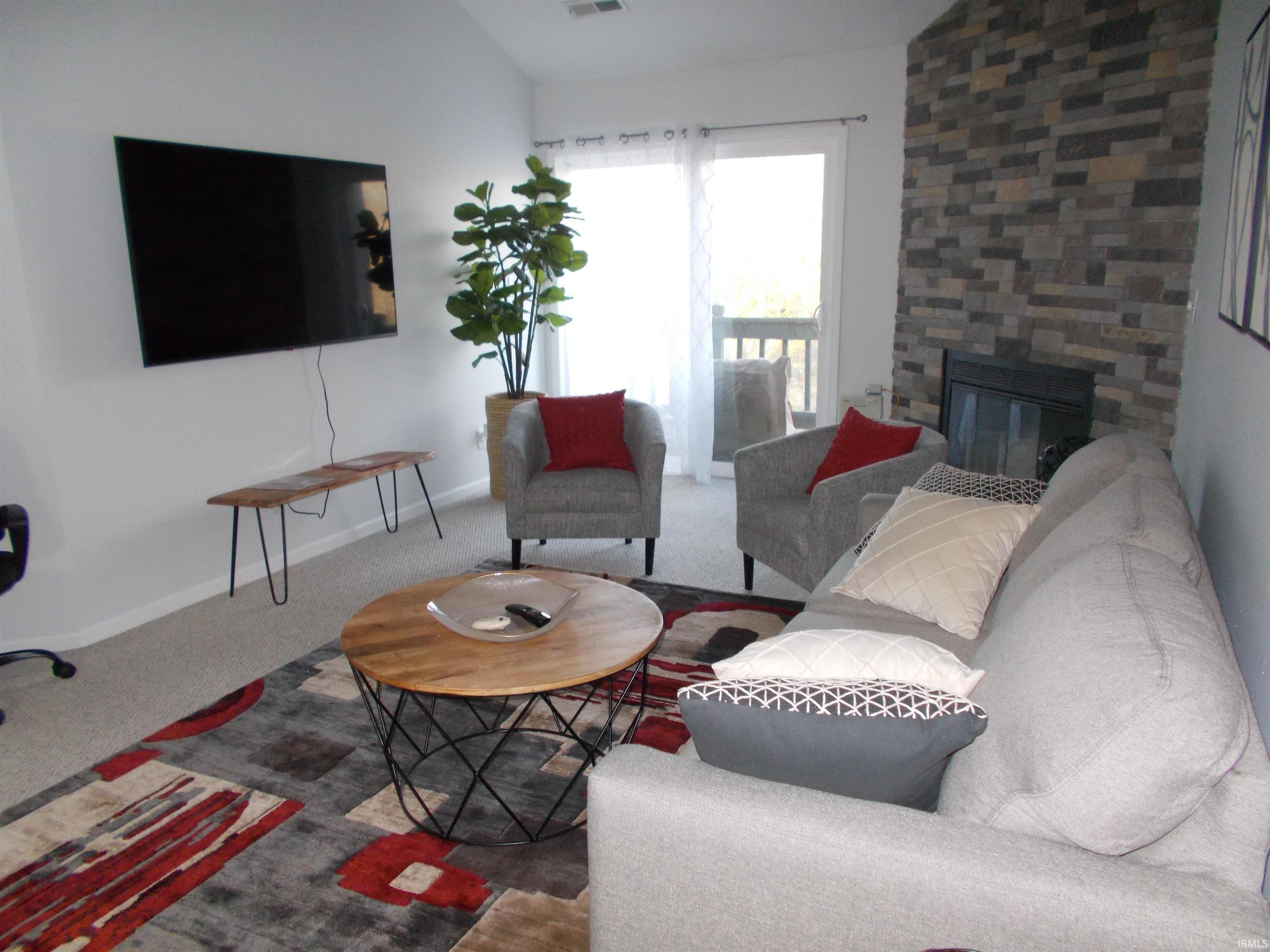 Image 3: Living room featuring vaulted ceiling, a fireplace, and carpet floors, Living Room