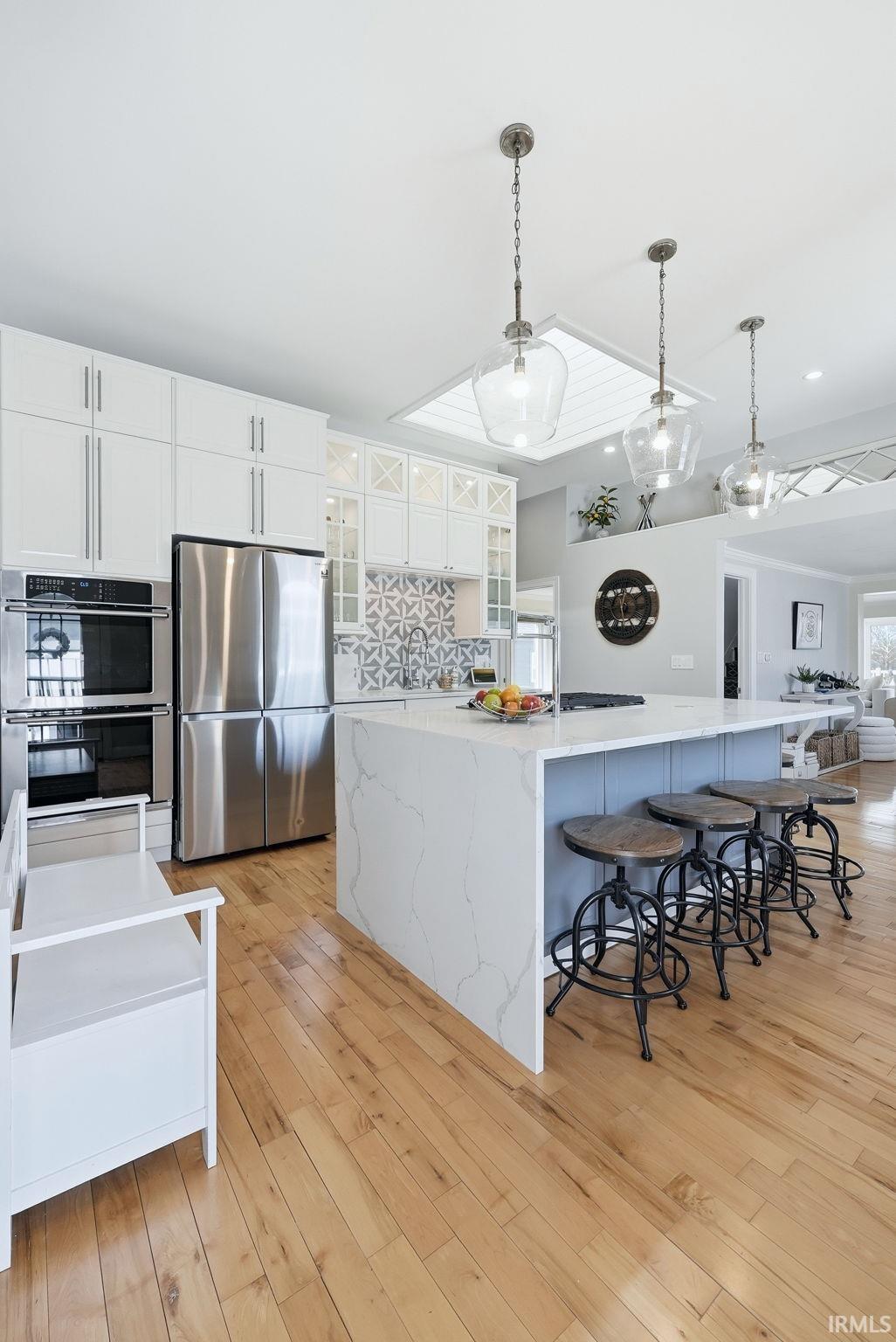 Image 3: Kitchen featuring white cabinetry, pendant lighting, a spacious island, stainless steel appliances, and a kitchen bar, Kitchen