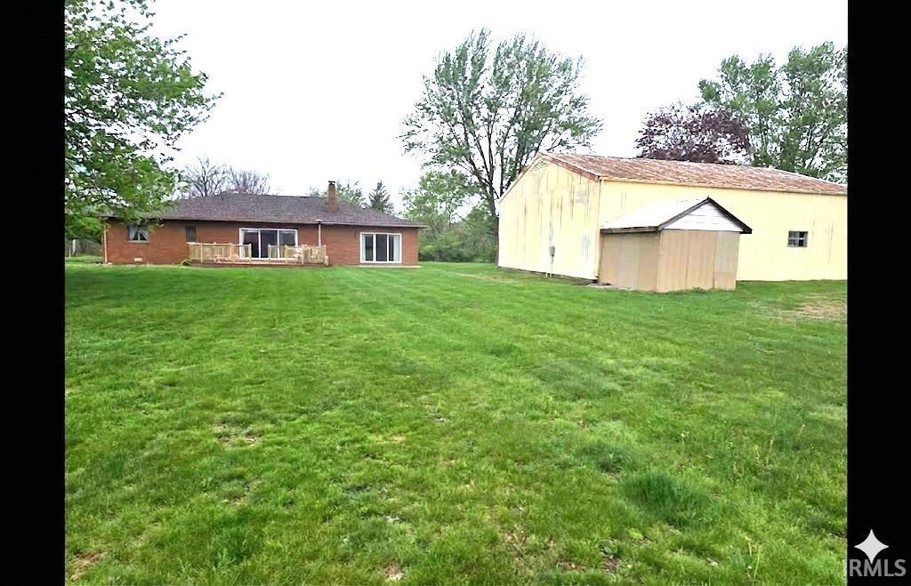 Image 1: Back of property with a chimney, a lawn, a storage shed, and a deck, Back Of Structure Image 1: Back of property with a chimney, a lawn, a storage shed, and a deck, Back Of Structure