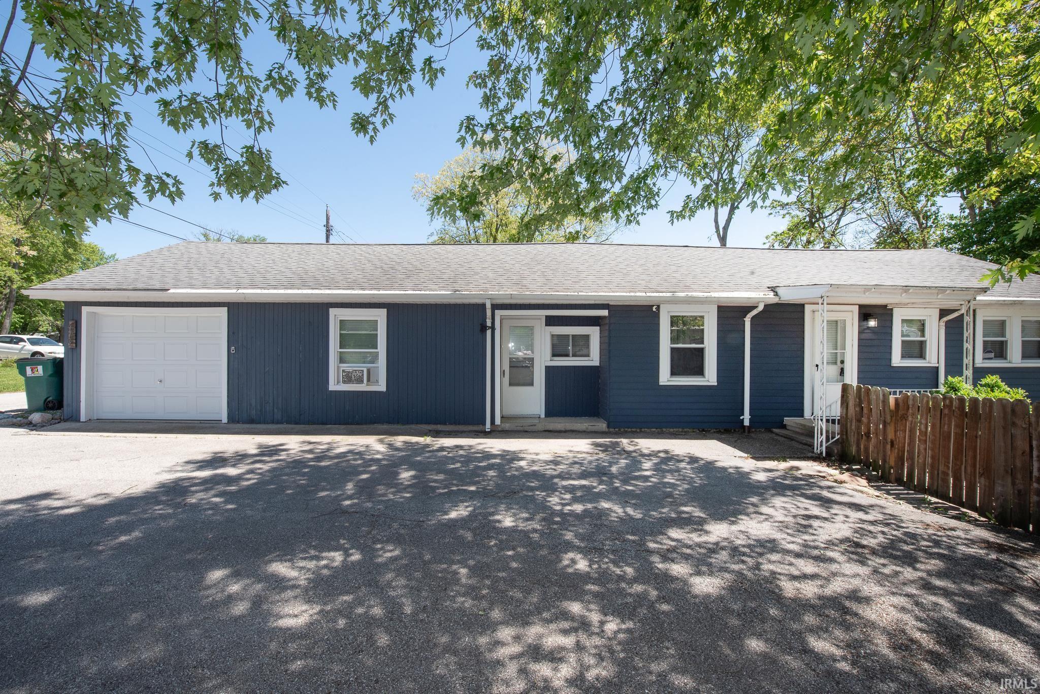Image 0: Exterior featuring blue siding, white trim windows, white entry doors, and a single-car garage, Front Of Structure Image 0: Exterior featuring blue siding, white trim windows, white entry doors, and a single-car garage, Front Of Structure