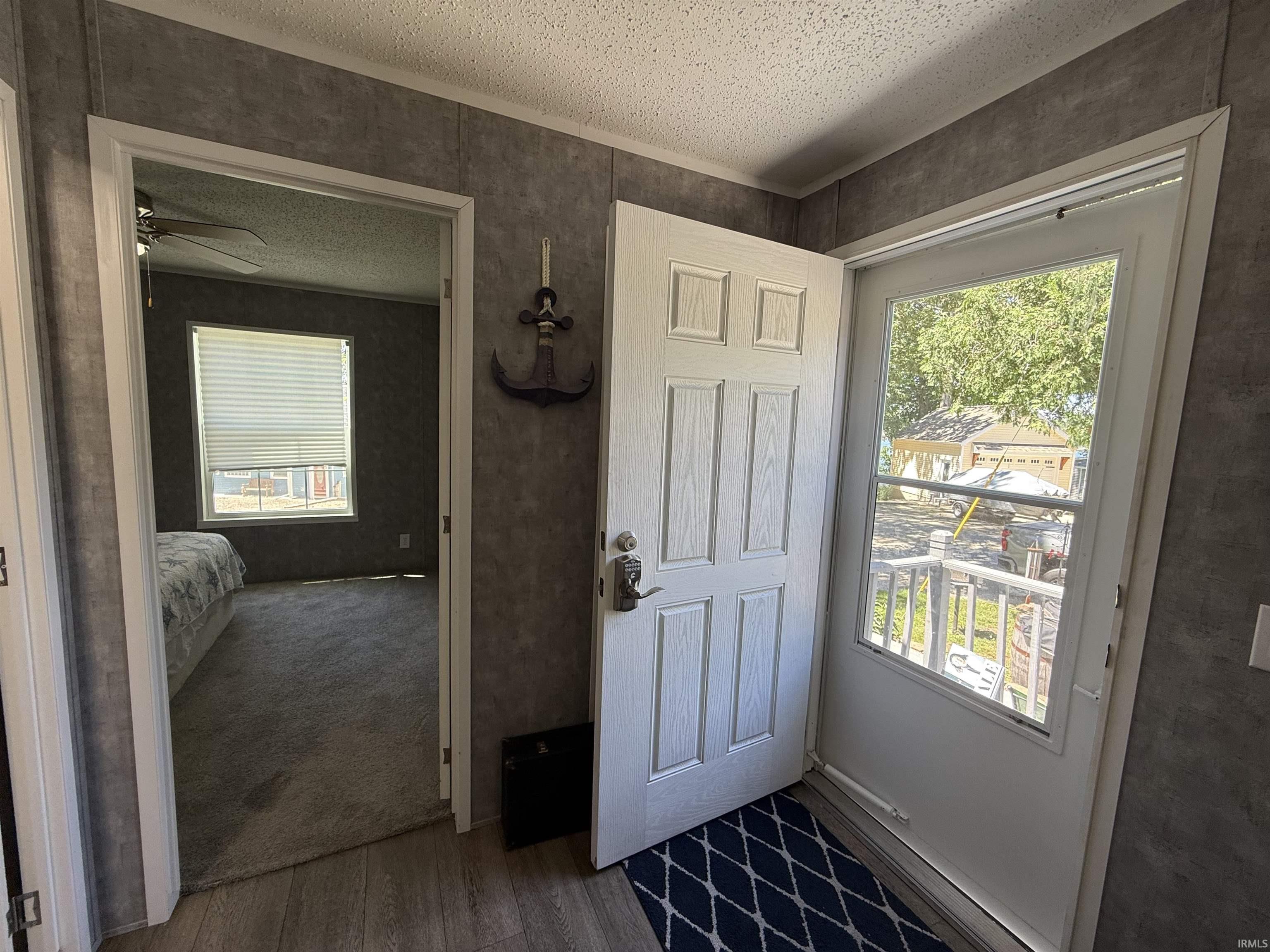 Image 3: Entryway featuring wood-finish flooring, textured wall paneling, and a white paneled door, Entry