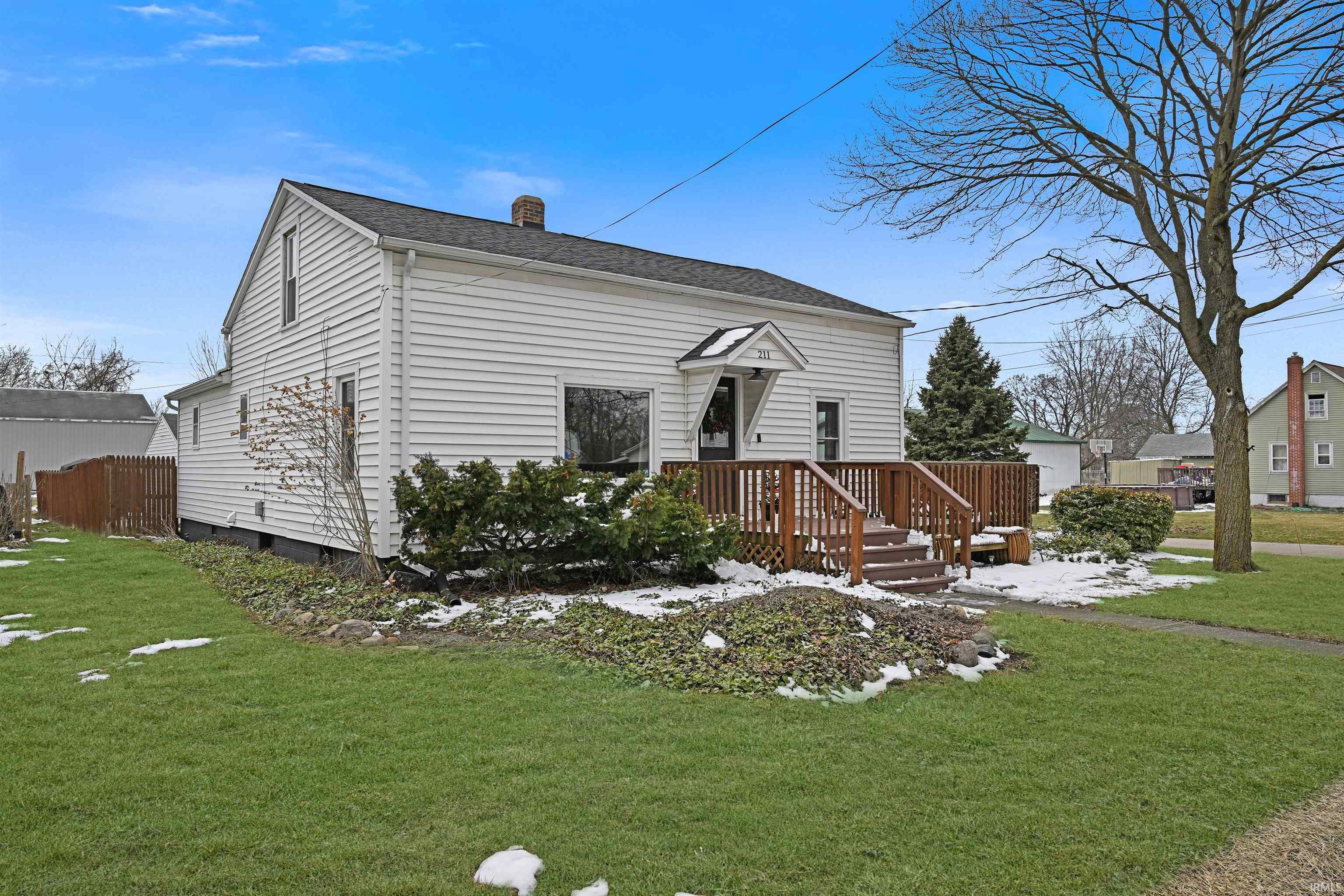 Image 2: View of front of property featuring a front lawn, a chimney, a deck, and a shingled roof, Front Of Structure