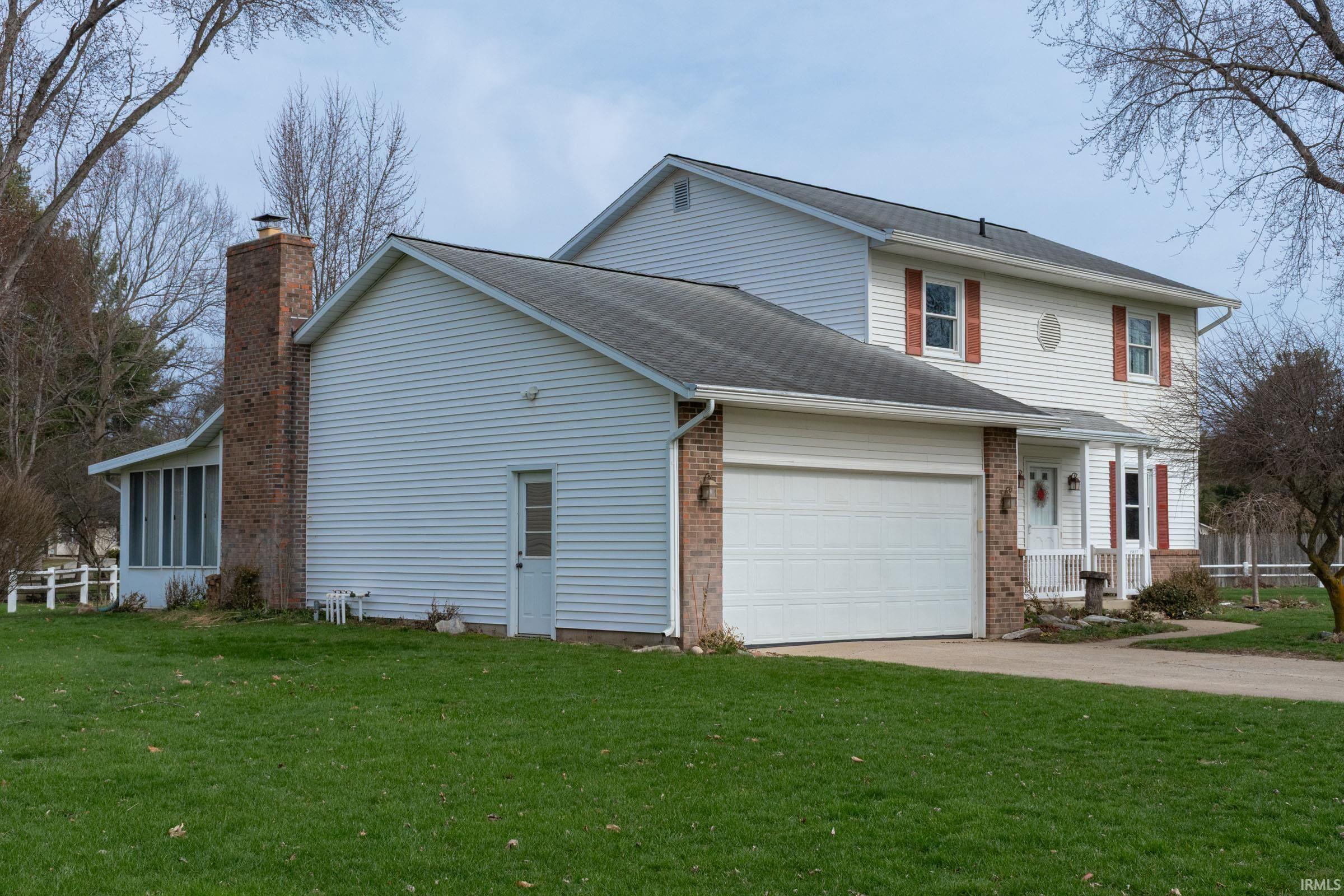 Image 1: View of home's exterior featuring brick siding, concrete driveway, a garage, roof with shingles, and a chimney, Side Of Structure
