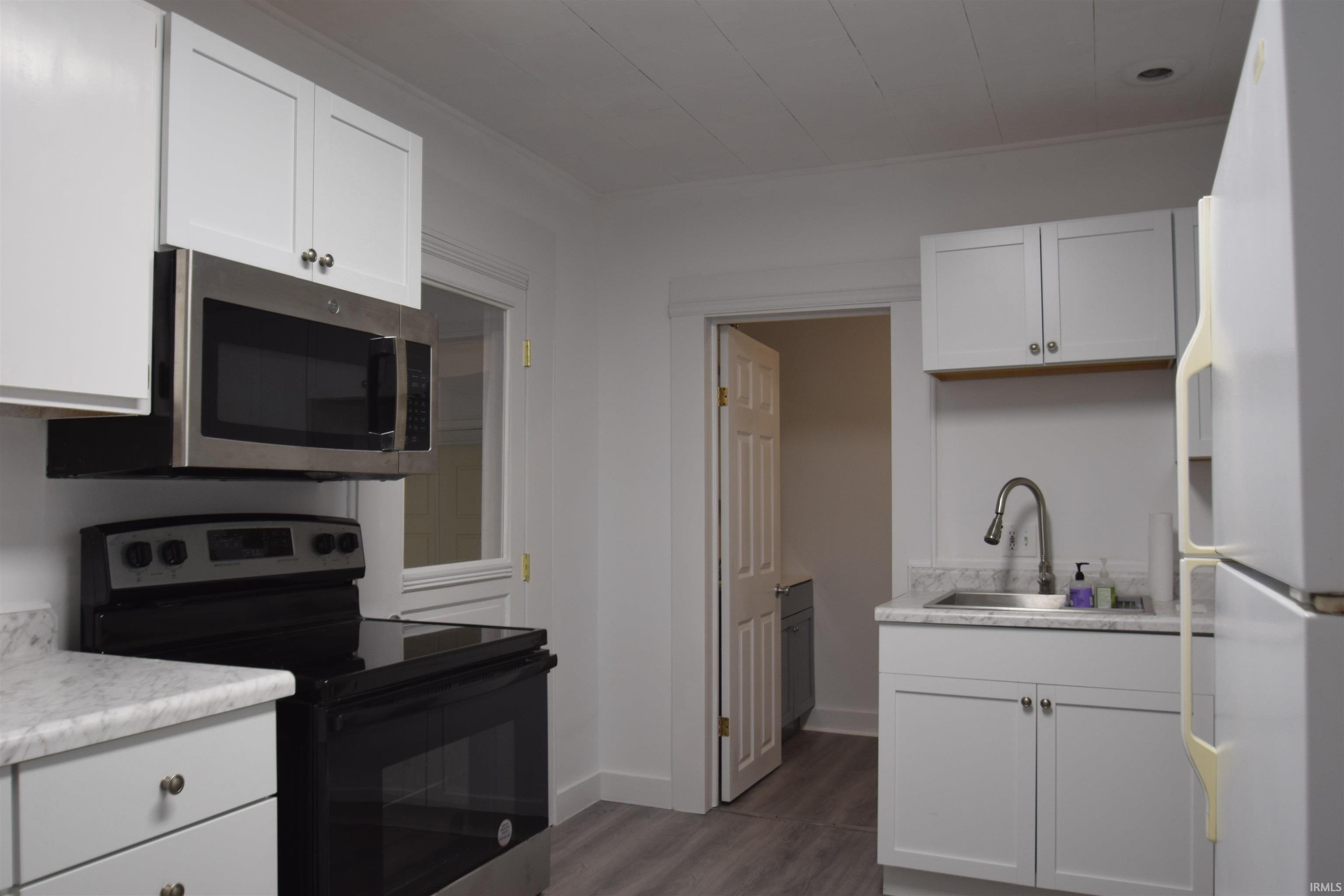 Image 2: Kitchen featuring stainless steel appliances, light countertops, white cabinets, and dark wood finished floors, Kitchen