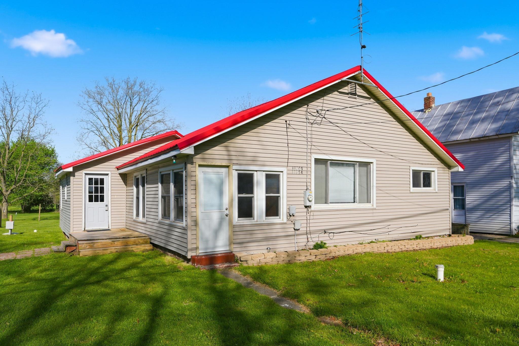 Image 0: Exterior featuring neutral-toned siding, a vibrant red roof, multiple windows, and a green lawn, Back Of Structure