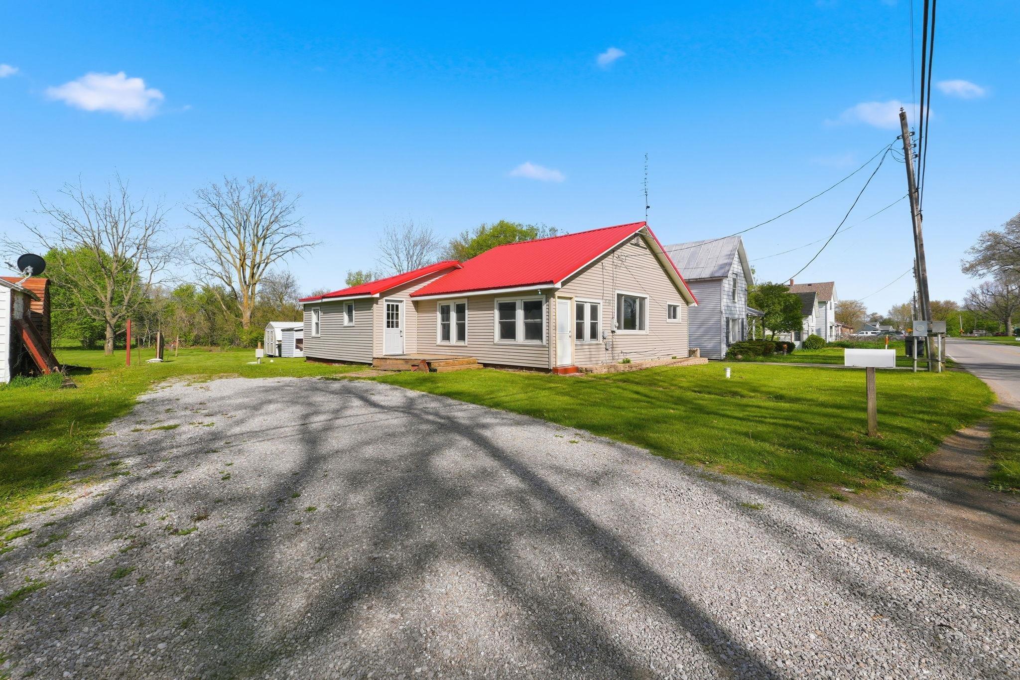 Image 1: Single-story home featuring a vibrant red roof and light-colored siding, Front Of Structure