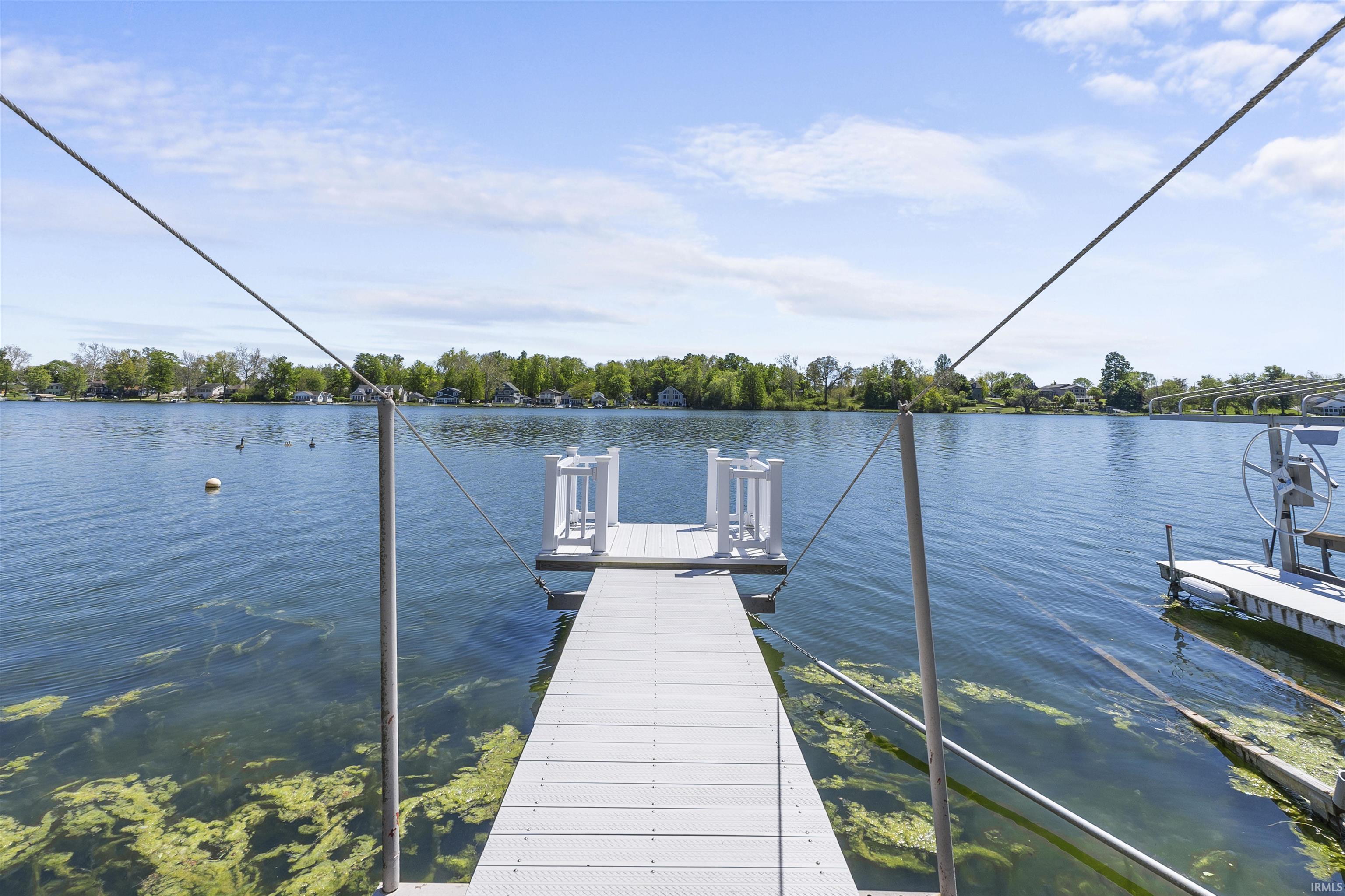 Image 1: Expansive dock extending into a body of water, featuring a boat lift and a clear view of the distant shoreline, Dock Image 1: Expansive dock extending into a body of water, featuring a boat lift and a clear view of the distant shoreline, Dock