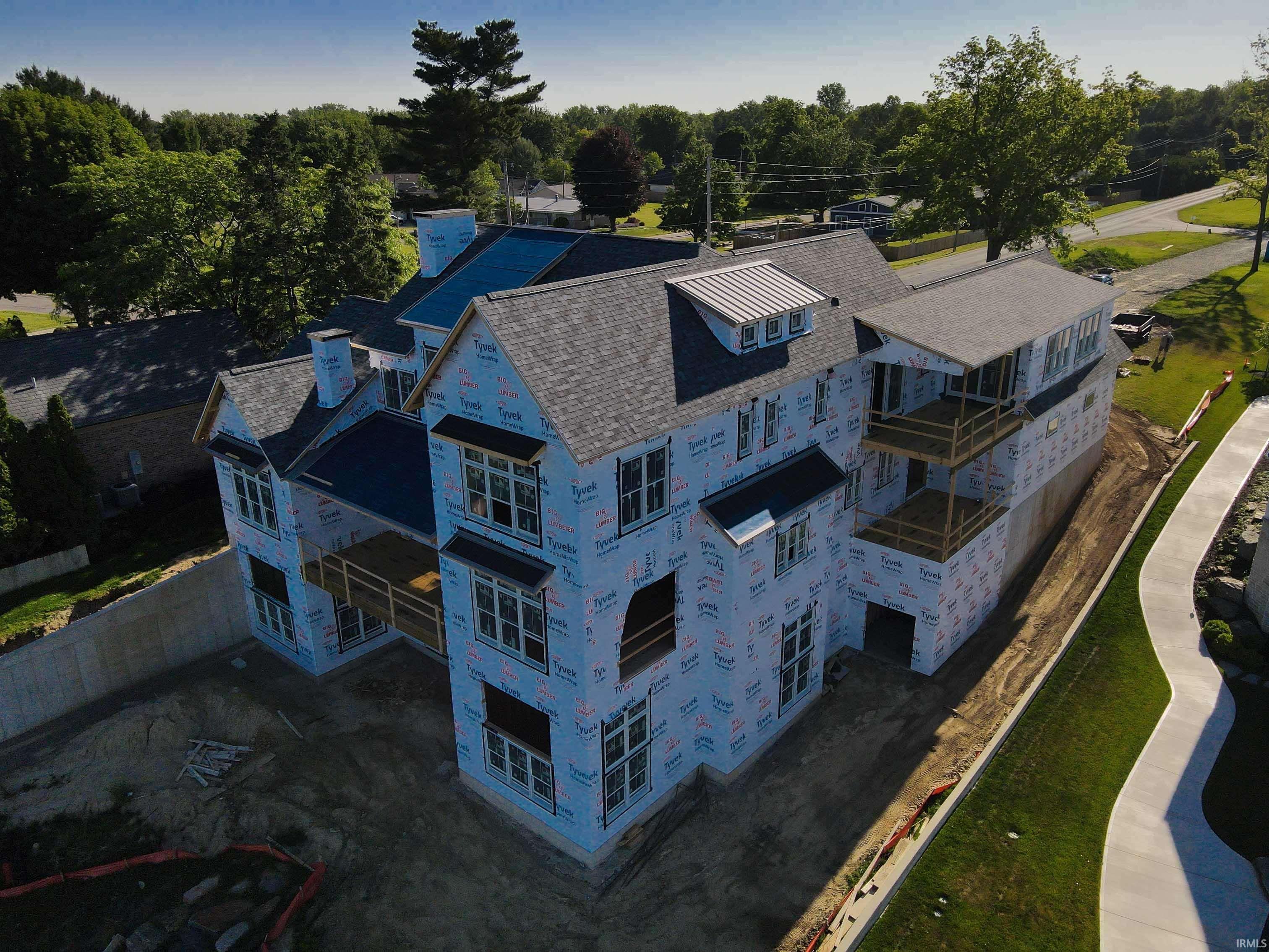 Image 3: Expansive multi-story residence under construction featuring a shingled roof, multiple balconies, and a concrete retaining wall, Aerial View