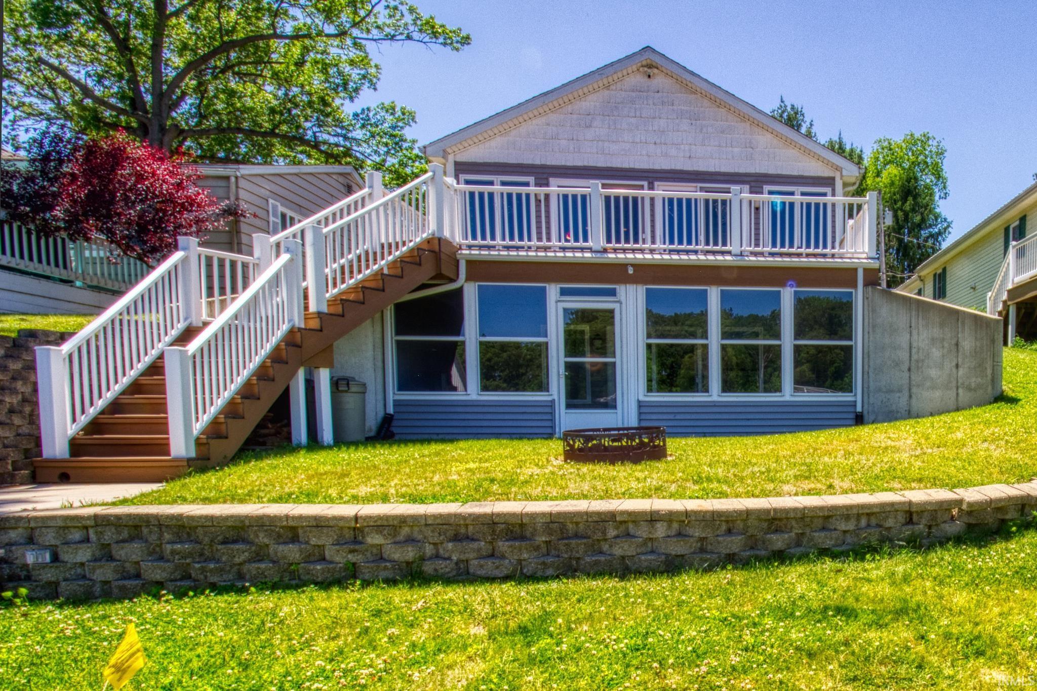 Image 0: Ranch with walkout lower-level patio with multiple windows, an upper-level balcony with white railings, and an exterior staircase with white railings, Lakeside View Image 0: Ranch with walkout lower-level patio with multiple windows, an upper-level balcony with white railings, and an exterior staircase with white railings, Lakeside View