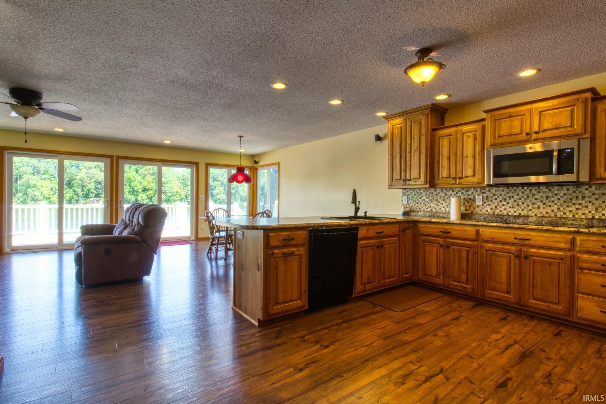 Image 2: Open-concept kitchen and living area featuring wood-finish flooring, recessed lighting, and a ceiling fan, Kitchen Image 2: Open-concept kitchen and living area featuring wood-finish flooring, recessed lighting, and a ceiling fan, Kitchen
