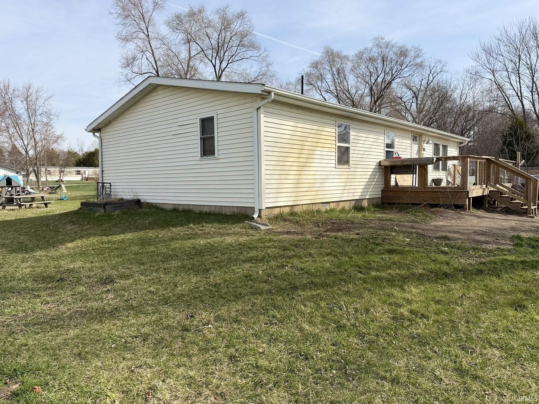 Image 1: View of property exterior featuring a wooden deck and a lawn, Side Of Structure Image 1: View of property exterior featuring a wooden deck and a lawn, Side Of Structure