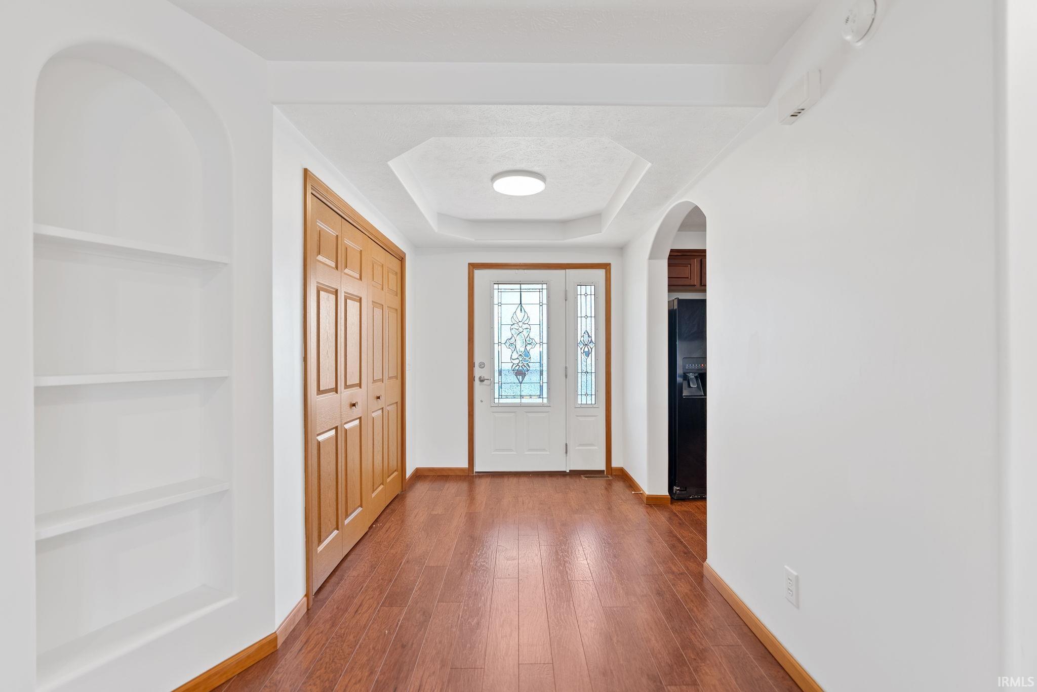 Image 3: Entryway featuring wood-finish flooring, a decorative tray ceiling with flush-mount lighting, and a double-door entry with leaded glass inserts, Entrance Foyer