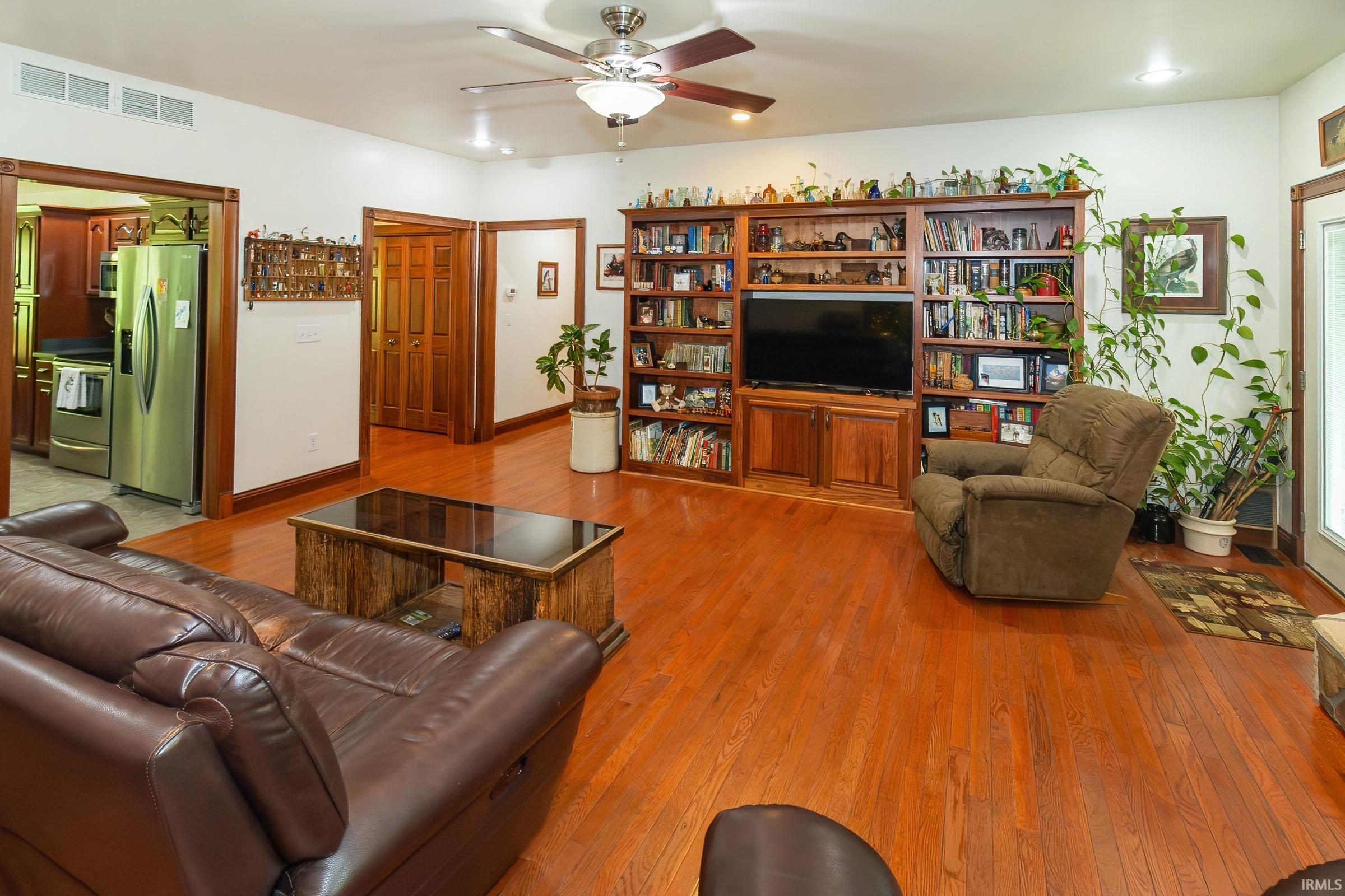 Image 3: Living space featuring rich wood-finish (Hardwood) flooring and a built-in entertainment center with extensive shelving, Living Room Image 3: Living space featuring rich wood-finish (Hardwood) flooring and a built-in entertainment center with extensive shelving, Living Room