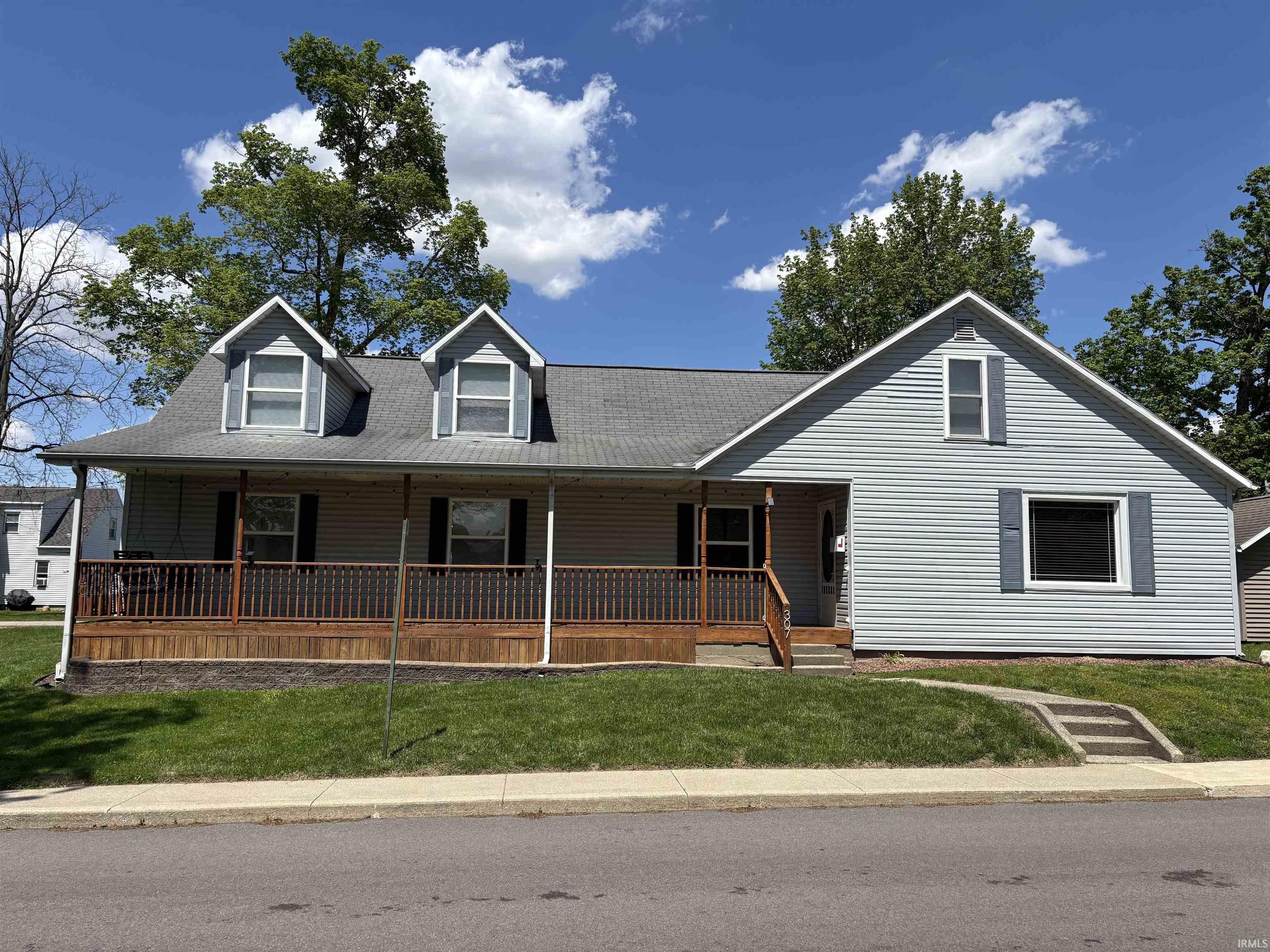 Image 3: Light gray siding exterior with a covered front porch featuring wood railings, two dormer windows, and a concrete walkway, Front Of Structure Image 3: Light gray siding exterior with a covered front porch featuring wood railings, two dormer windows, and a concrete walkway, Front Of Structure