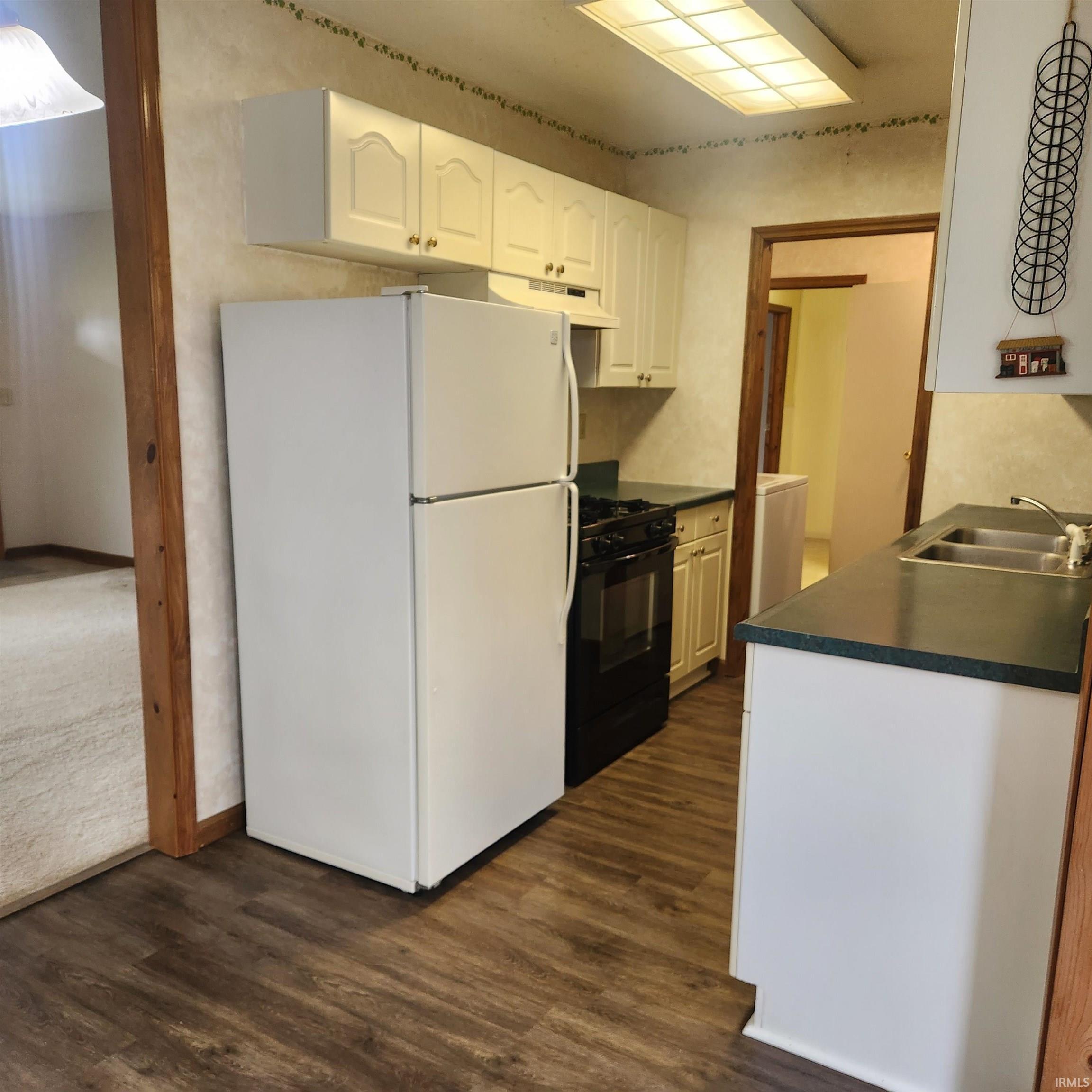 Image 2: Compact kitchen featuring wood-finish flooring, white cabinetry, dark countertops, a double basin sink, and a white refrigerator, Kitchen Image 2: Compact kitchen featuring wood-finish flooring, white cabinetry, dark countertops, a double basin sink, and a white refrigerator, Kitchen