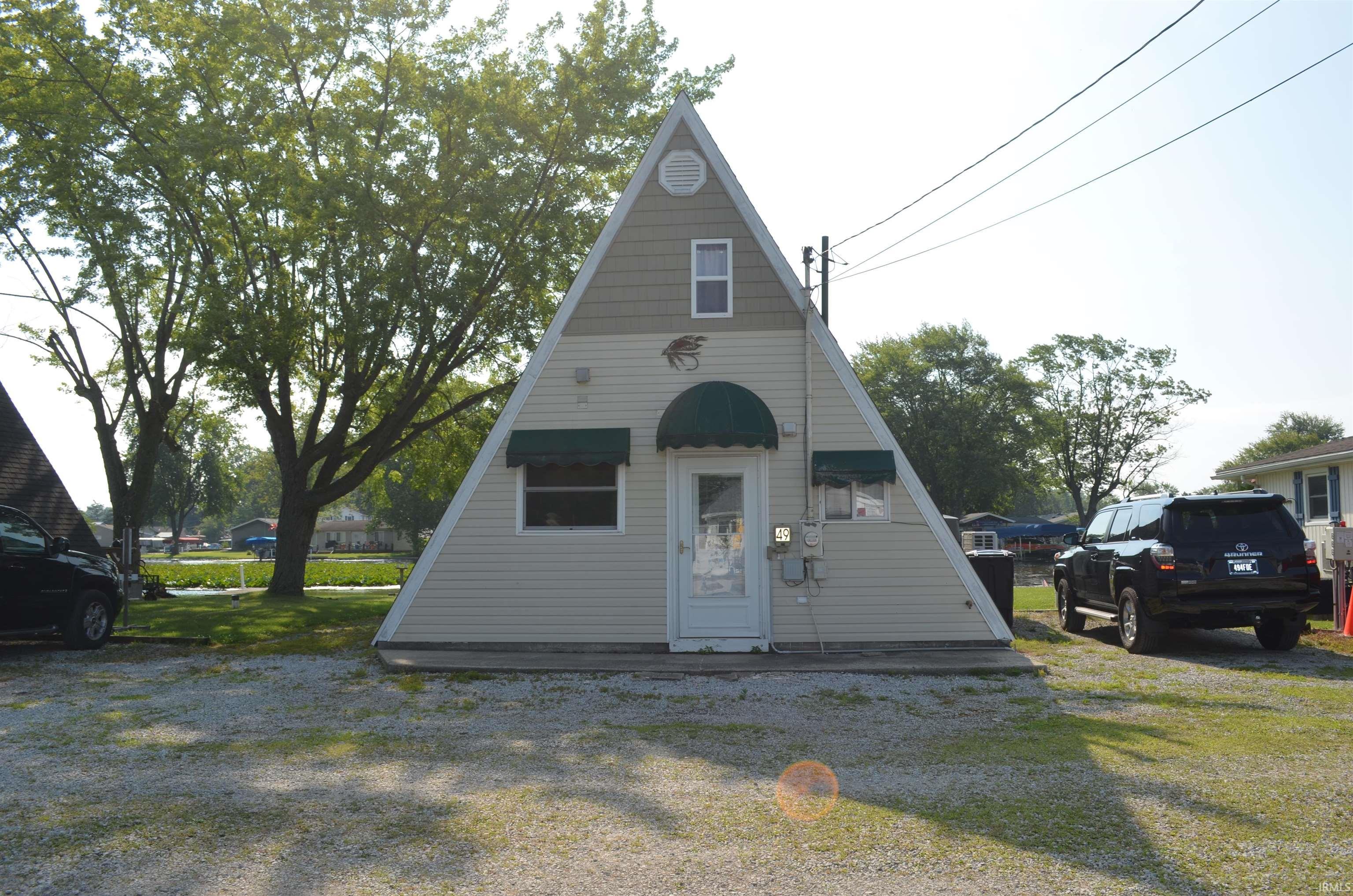 Image 0: A-frame structure featuring light-colored siding and a dark roofline, Front Of Structure