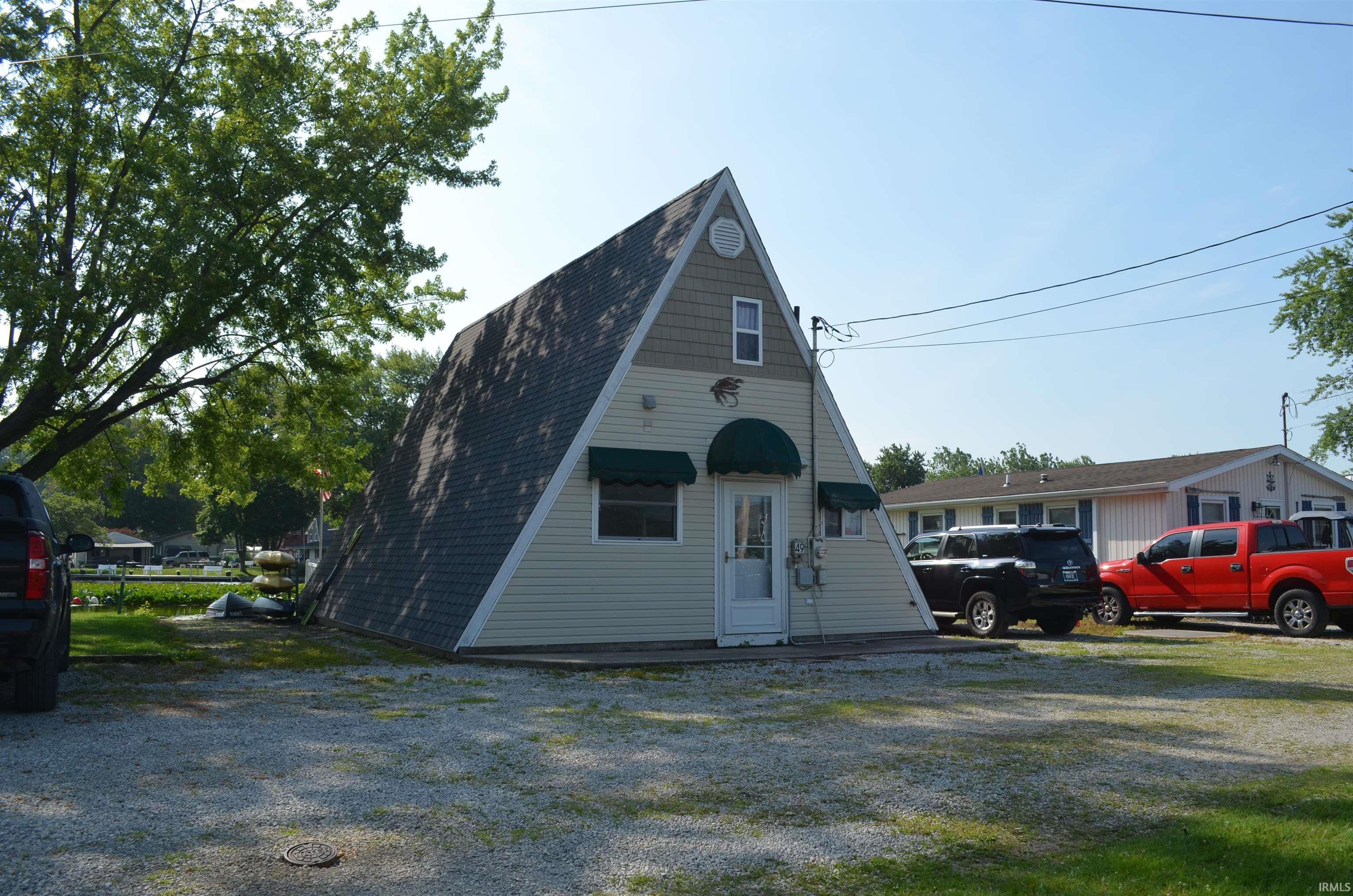Image 1: A-frame structure featuring light-colored siding and a contrasting shingled roof, Front Of Structure