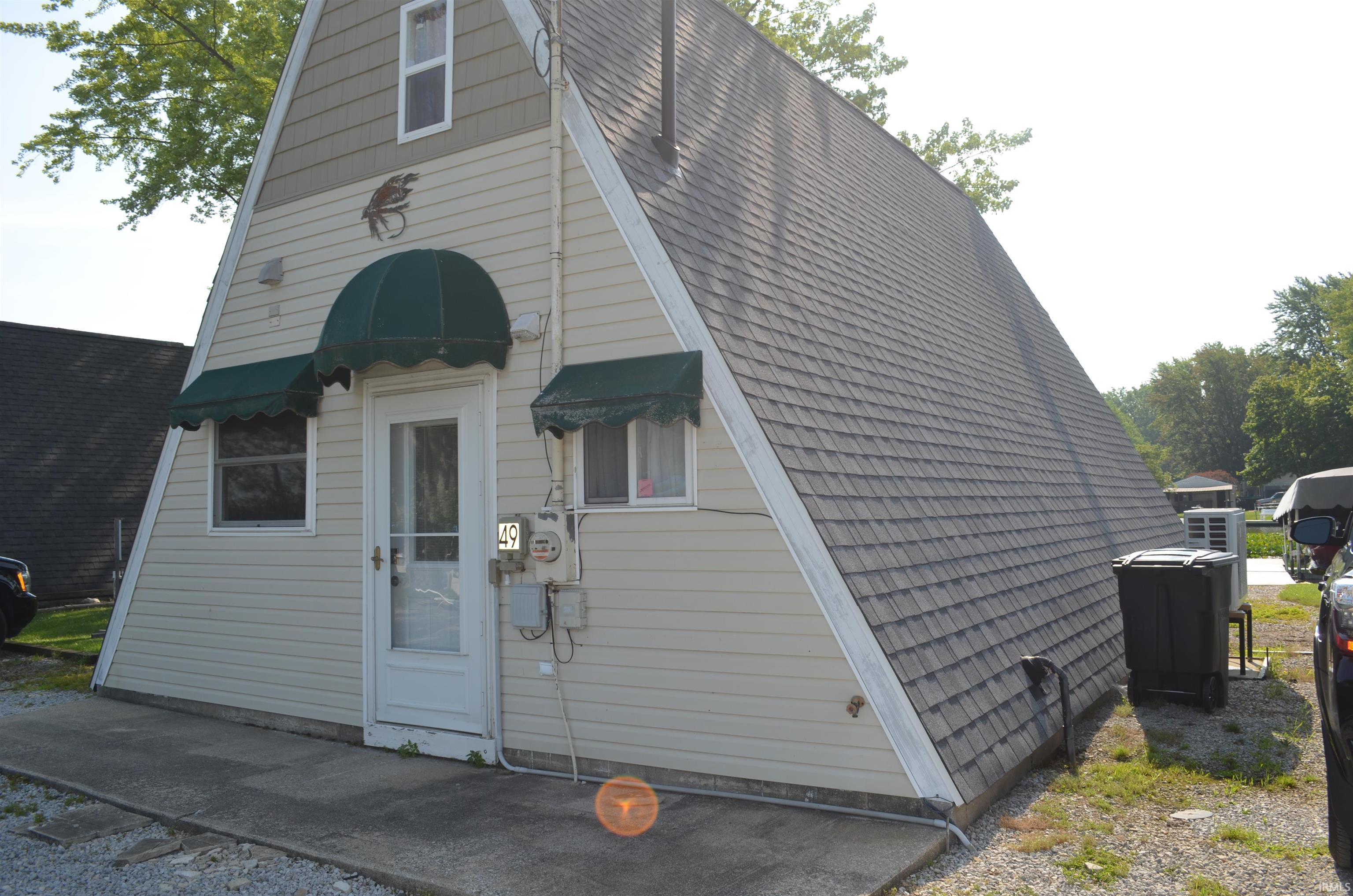 Image 2: A-frame structure featuring light-colored siding and a steeply pitched shingle roof, Front Of Structure