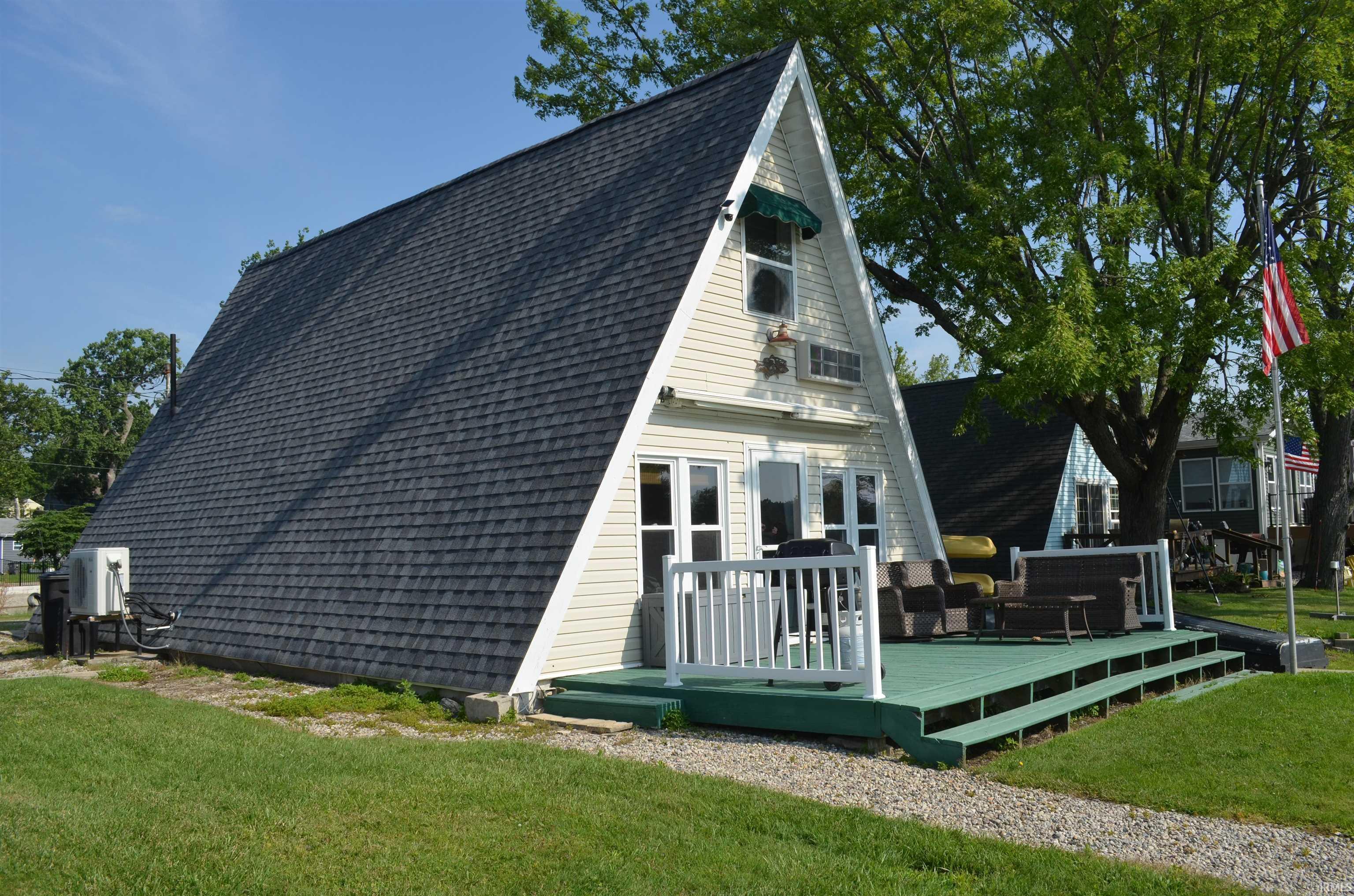 Image 3: A-frame residence featuring light-colored siding, a dark shingle roof, and a green-painted deck, Back Of Structure