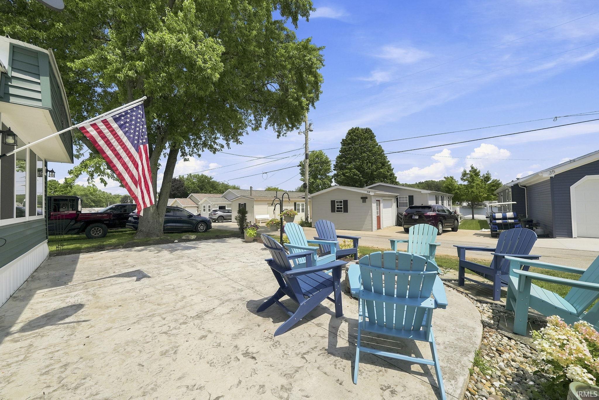 Image 1: Exterior patio area featuring concrete hardscaping, Adirondack chairs, and mature trees, Patio Image 1: Exterior patio area featuring concrete hardscaping, Adirondack chairs, and mature trees, Patio
