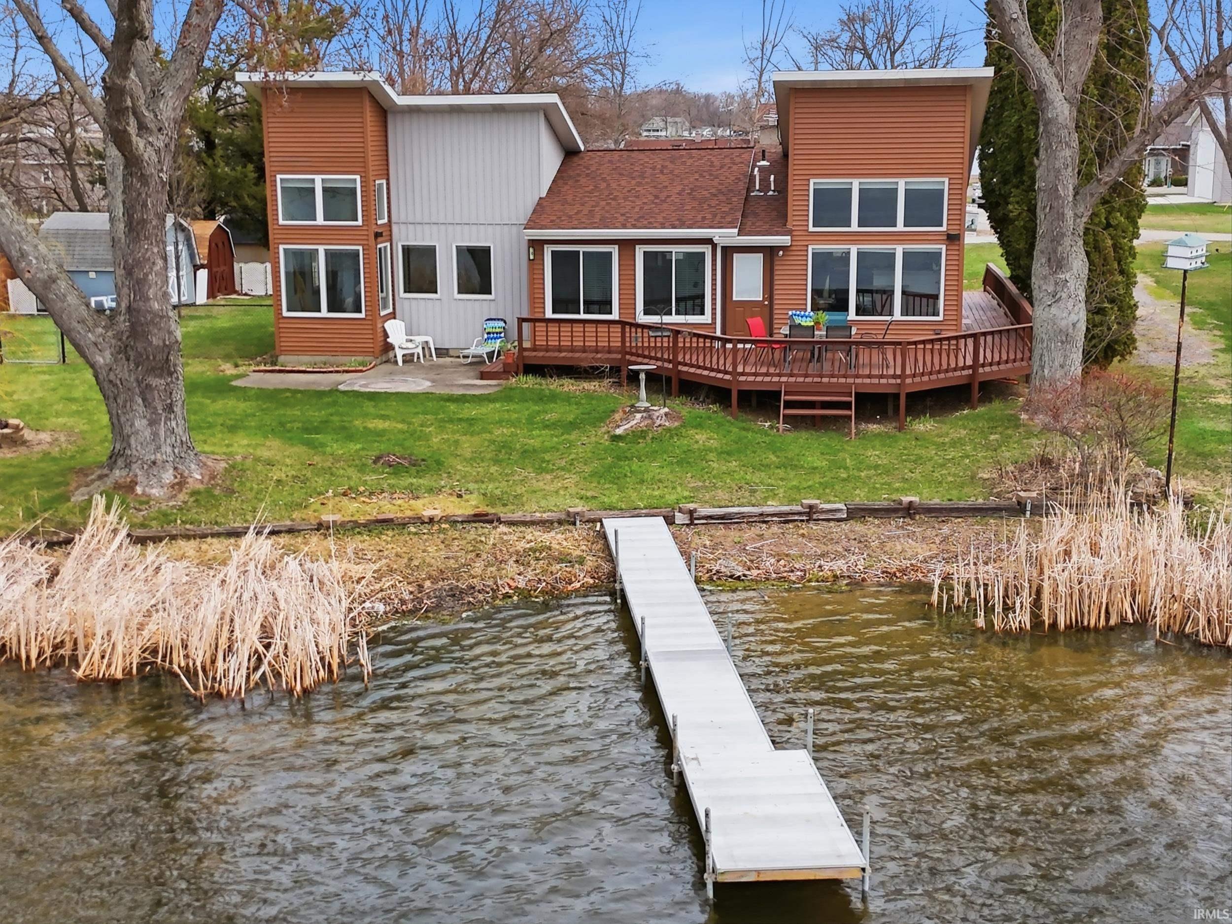 Image 0: Rear view of property featuring a yard, a patio area, a shingled roof, and a deck with water view, Back Of Structure