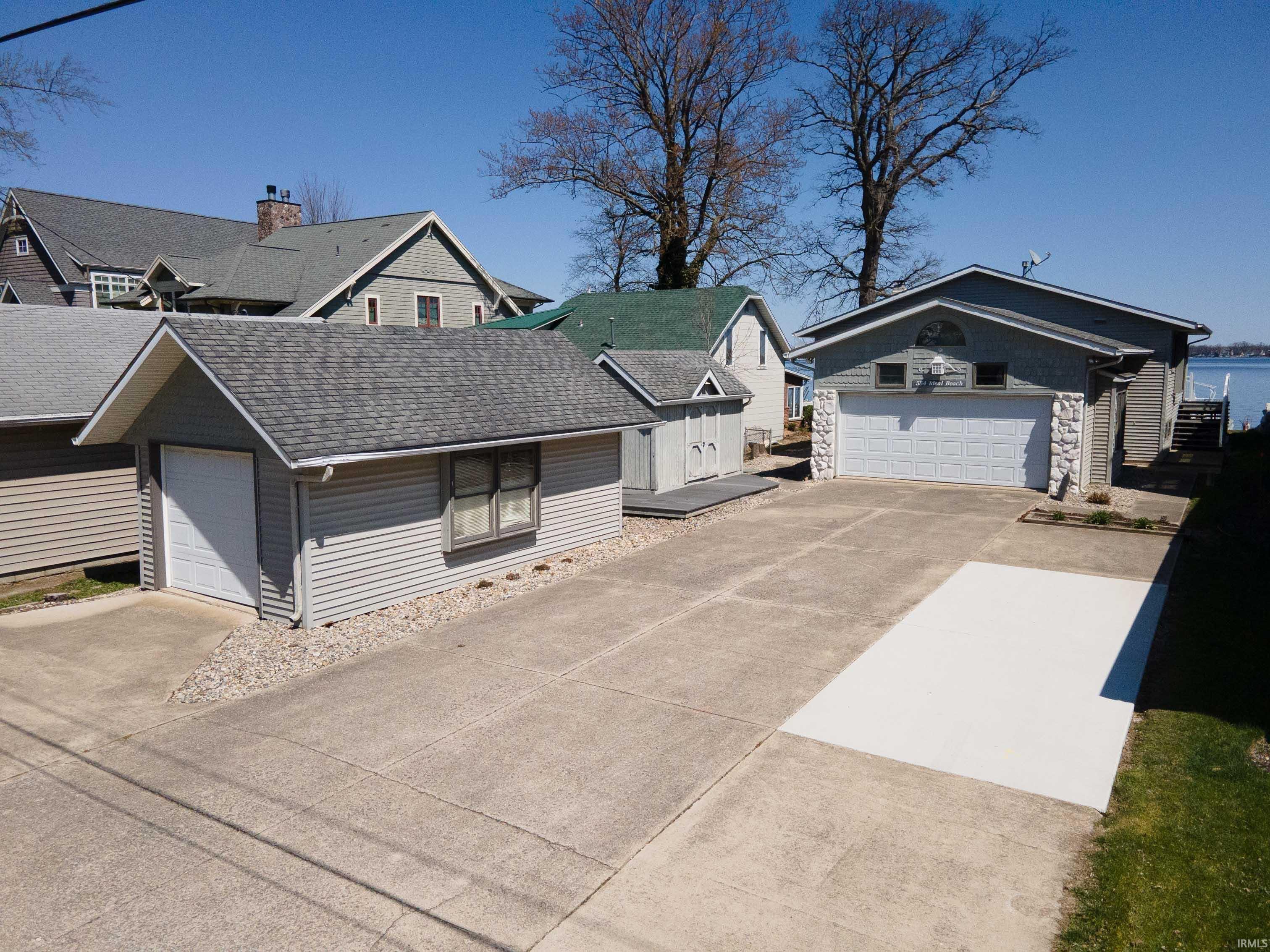 Image 1: View of front facade with a shingled roof, stone siding, a detached garage, and concrete driveway, Front Of Structure