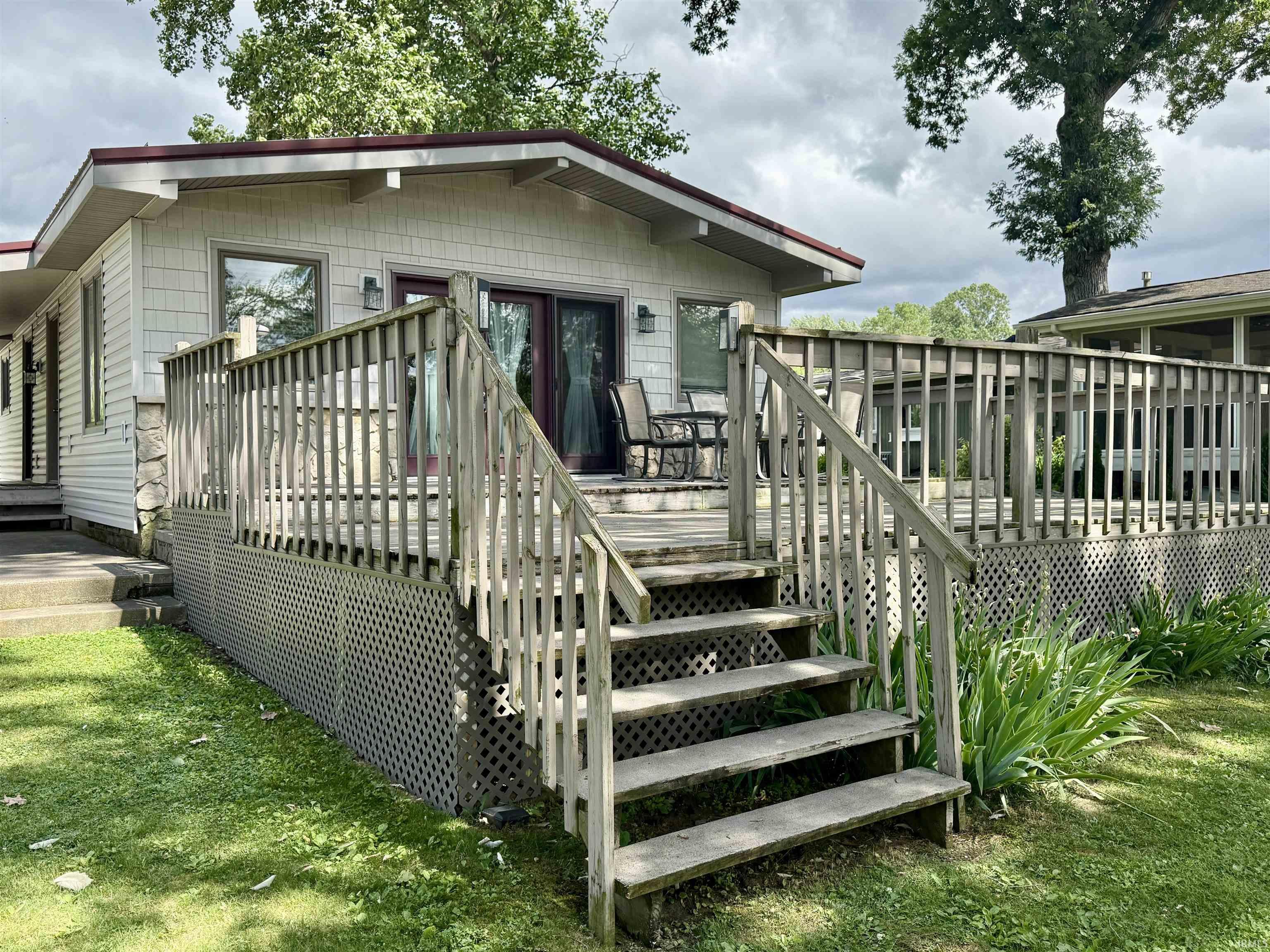 Image 3: Exterior featuring a spacious wood deck, red trim roof, white siding, and stone accents, Back Of Structure