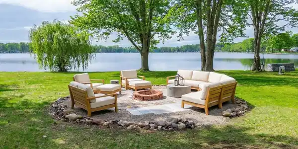Image 2: View of grassy yard with a water view, an outdoor living space with a fire pit, and a patio area, Lakefront firepit with virtual staging Image 2: View of grassy yard with a water view, an outdoor living space with a fire pit, and a patio area, Lakefront firepit with virtual staging