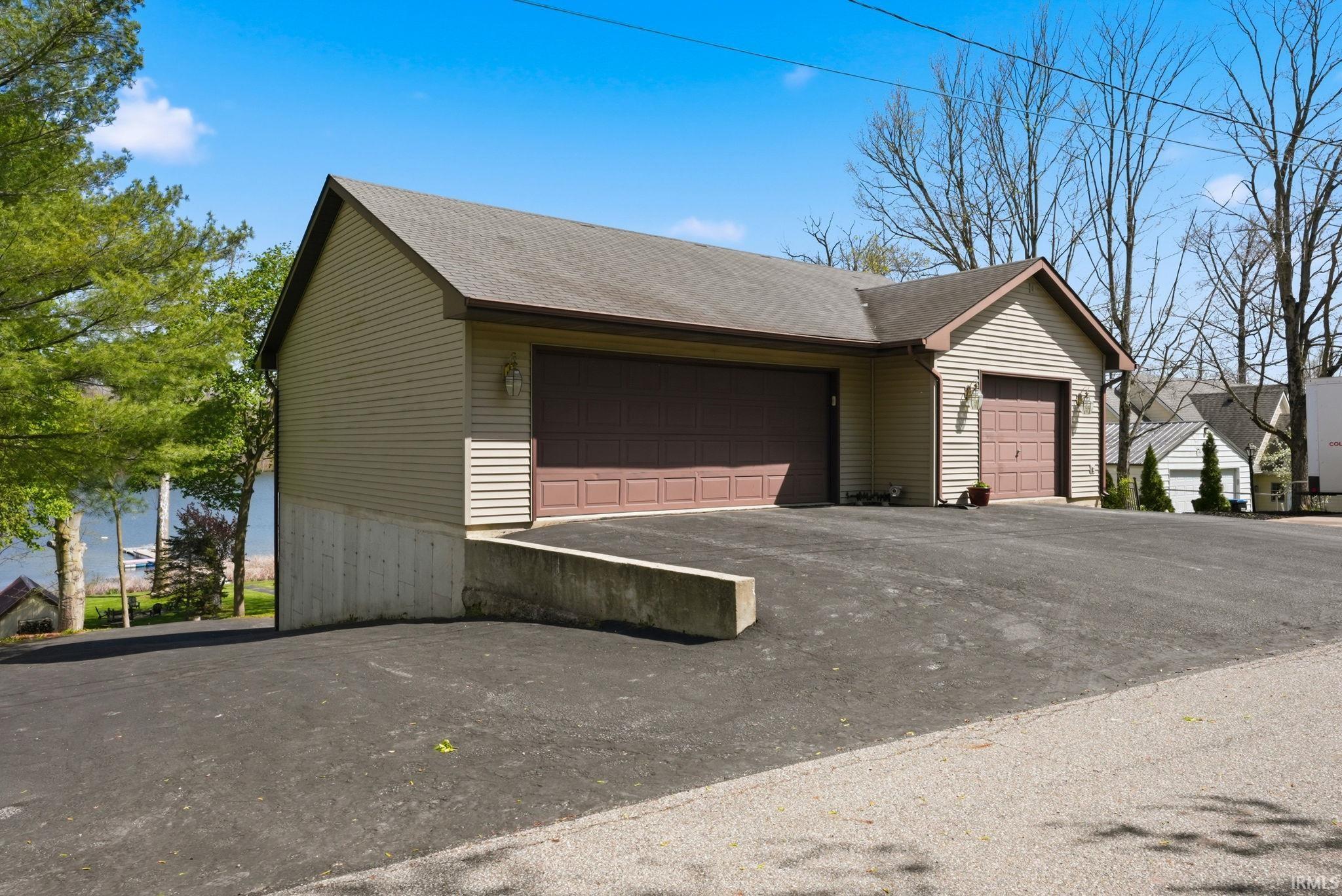 Image 2: Two-car garage with two distinct garage doors and light brown siding, Front Of Structure