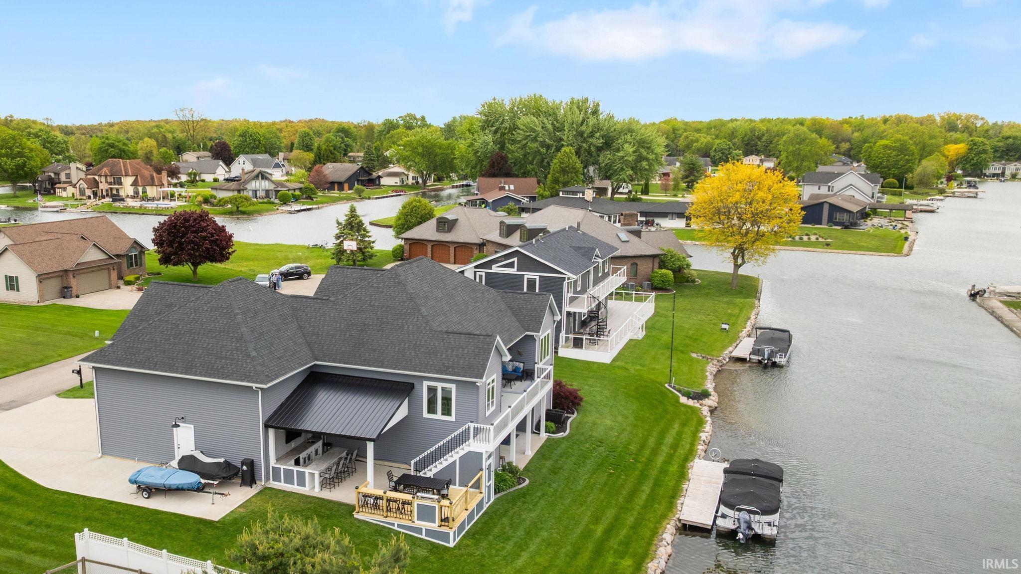 Image 1: Waterfront residence featuring a covered patio, multiple upper-level balconies, expansive green lawn, private boat dock, and direct water access, Aerial View