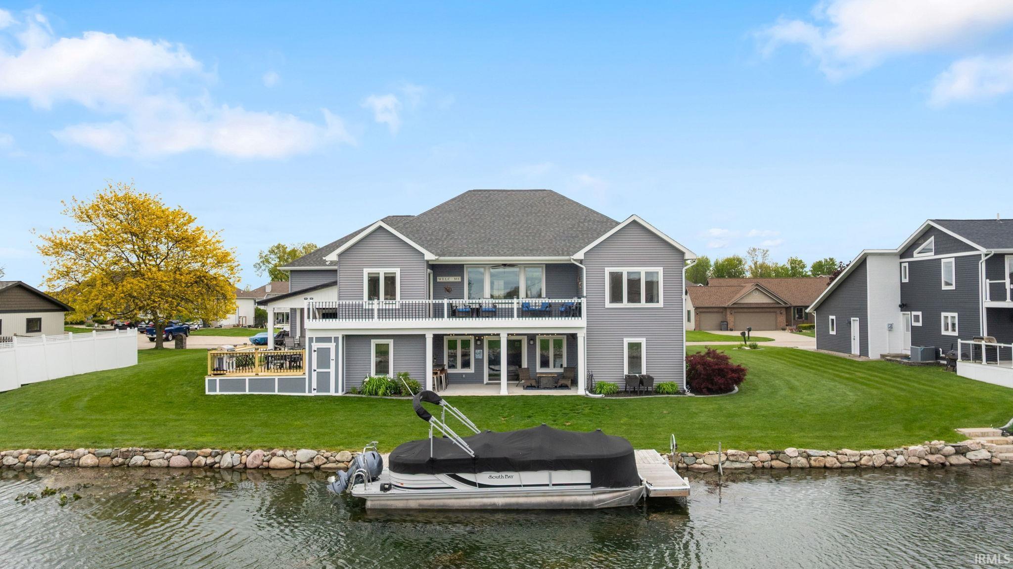 Image 2: Waterfront residence with a private dock featuring a boat, expansive green lawn, and a multi-level deck, Back Of Structure
