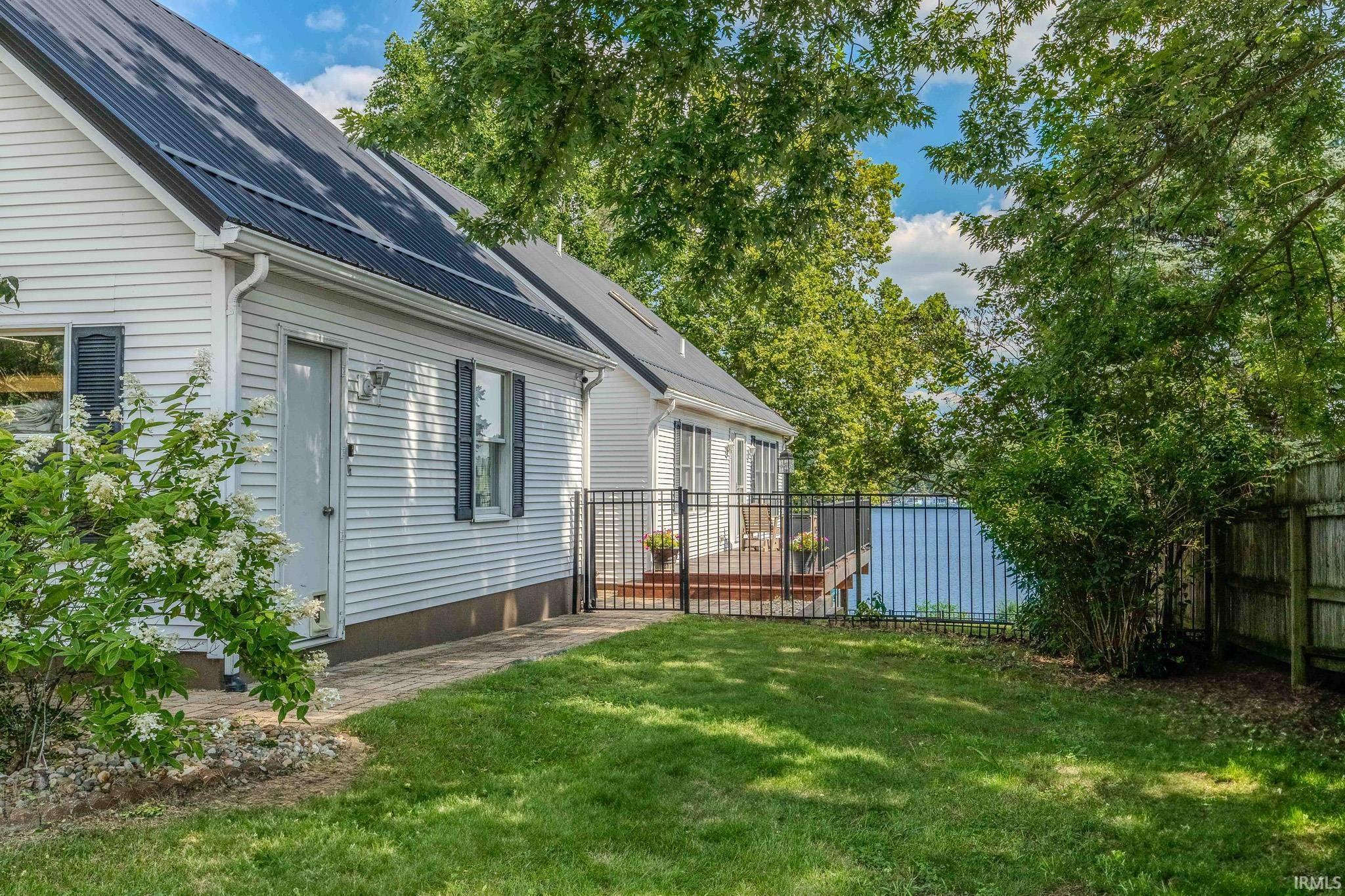 Image 3: White siding exterior with a dark metal roof, featuring a brick paver pathway, Yard