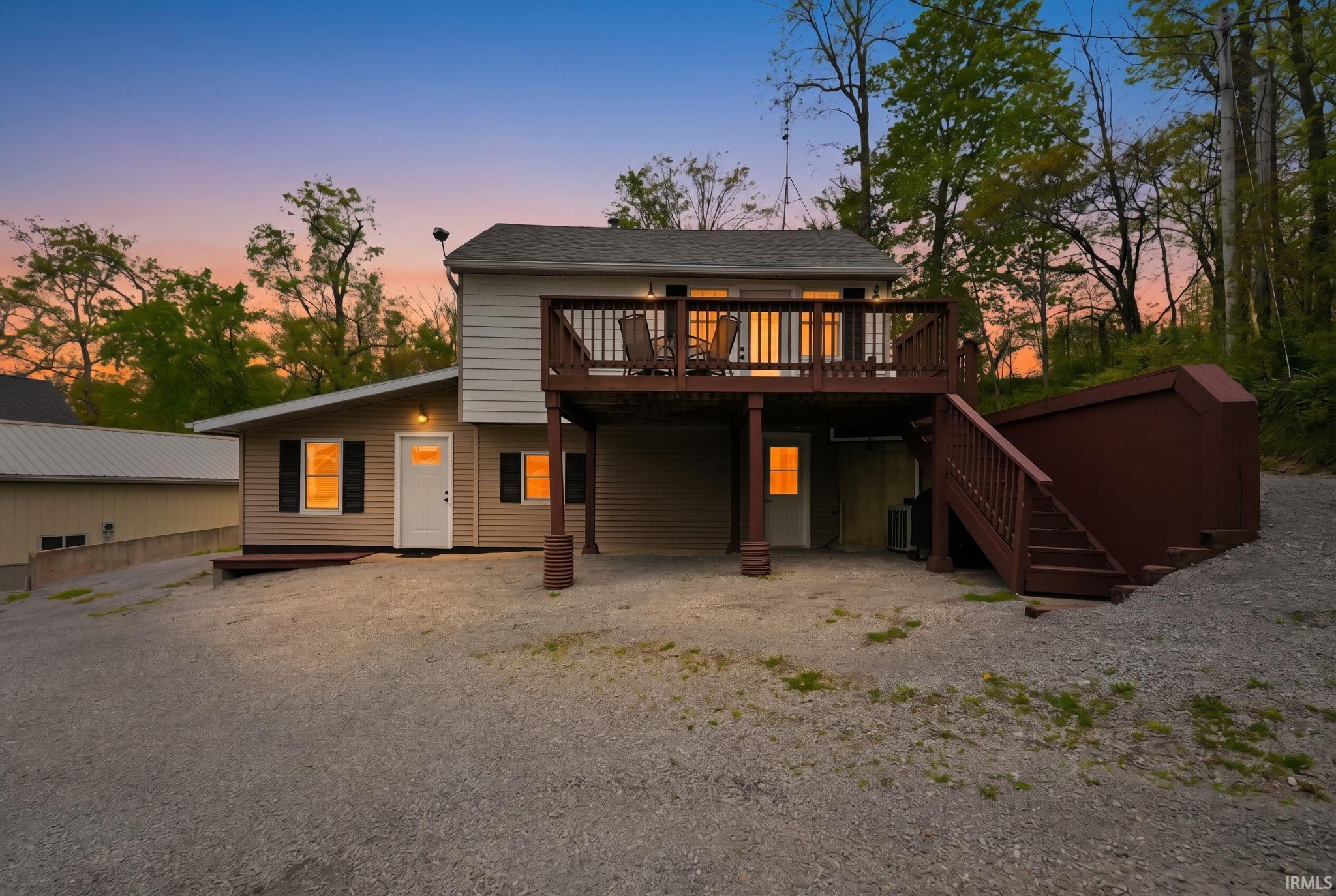 Image 1: Two-story property featuring a large upper deck with wood railing, tan siding, and black window shutters, Back Of Structure Image 1: Two-story property featuring a large upper deck with wood railing, tan siding, and black window shutters, Back Of Structure