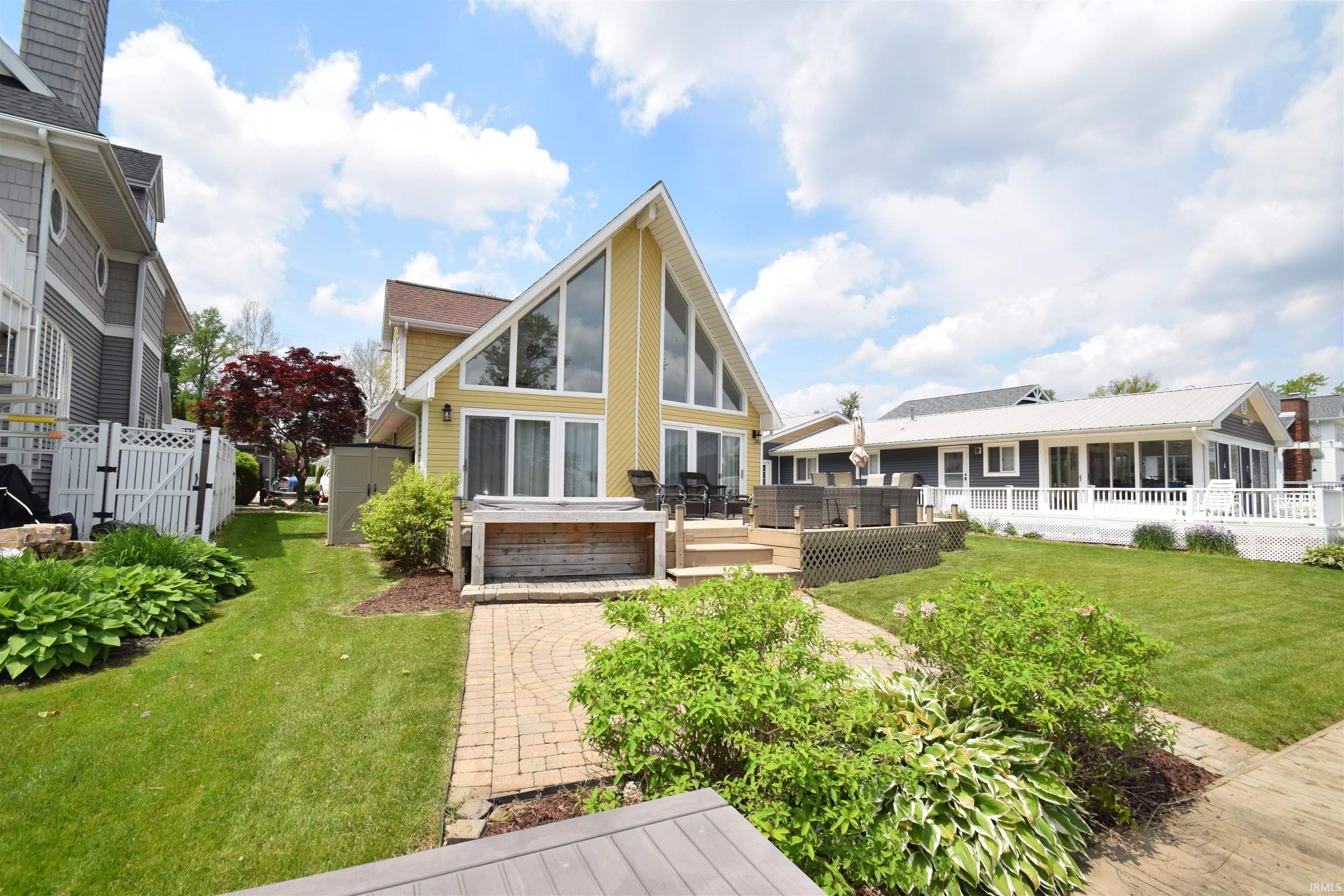 Image 0: Waterfront residence featuring a yellow vertical siding exterior with large apex windows and a brown shingle roof, HOME FROM THE WATERFRONT