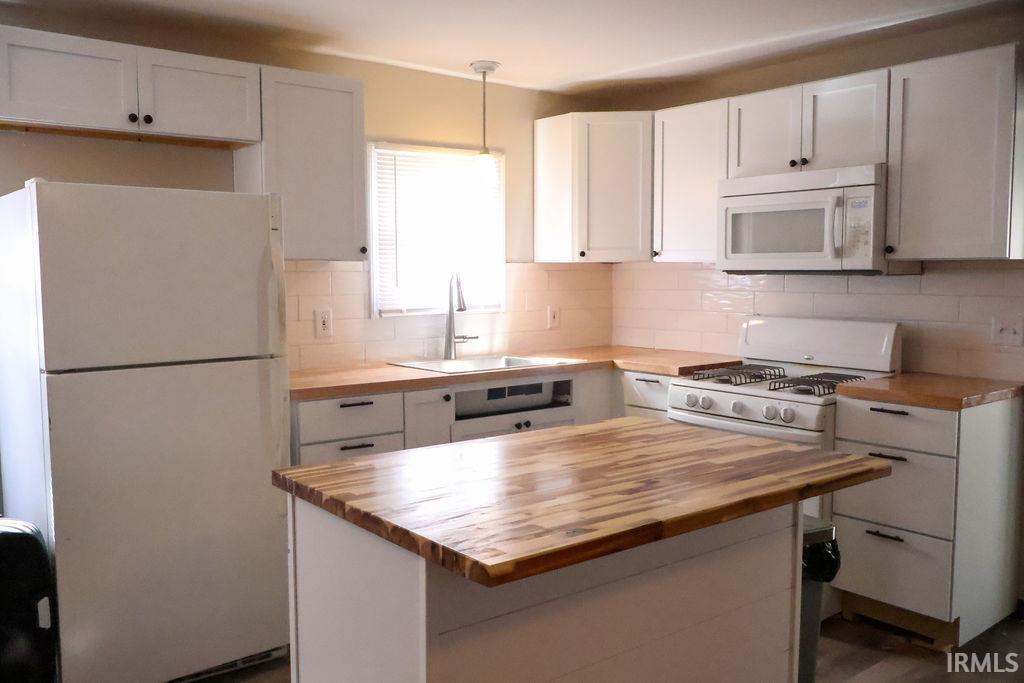Image 2: Kitchen featuring white cabinets, white appliances, decorative backsplash, and butcher block counters, Kitchen