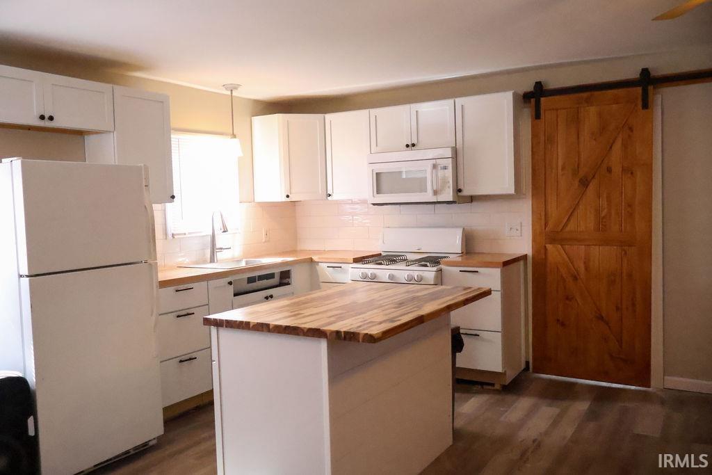 Image 3: Kitchen featuring white appliances, a barn door, white cabinetry, and butcher block countertops, Kitchen