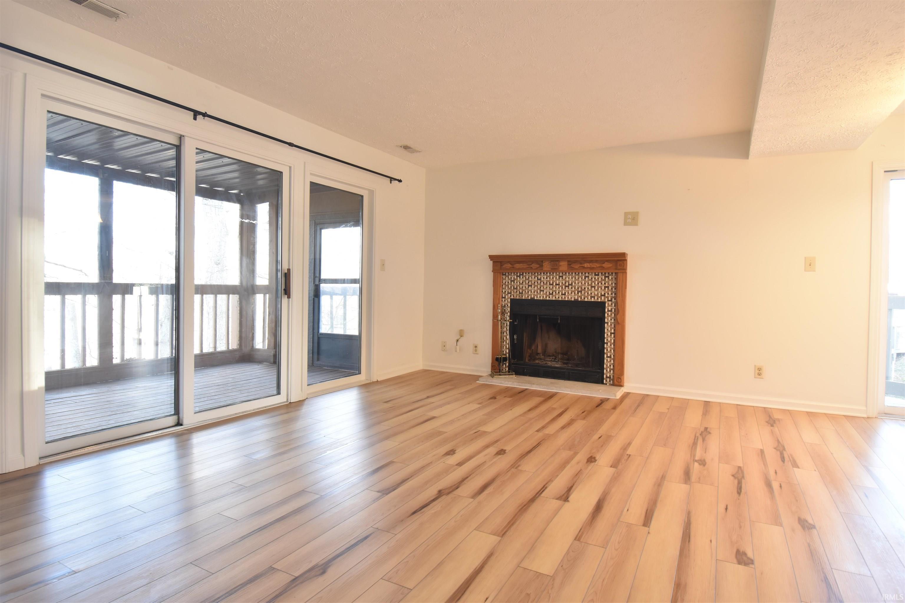 Image 2: Unfurnished living room with light wood finished floors and a tiled fireplace Image 2: Unfurnished living room with light wood finished floors and a tiled fireplace