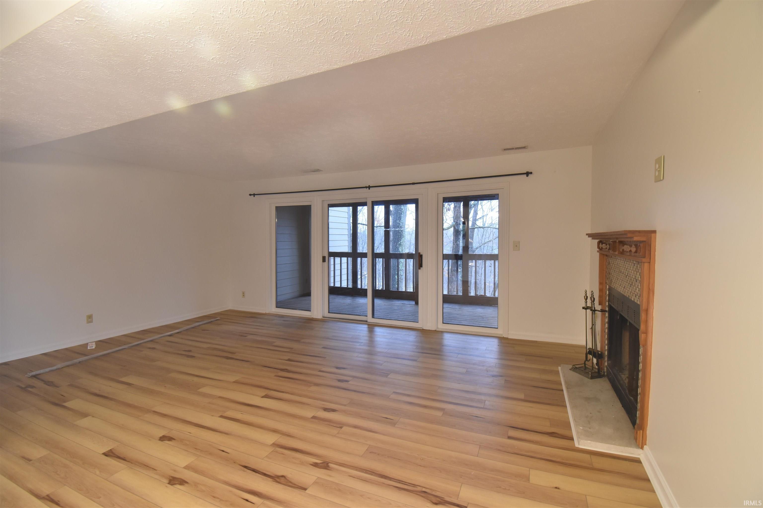 Image 3: Unfurnished living room with a fireplace, light wood-style floors, and a textured ceiling Image 3: Unfurnished living room with a fireplace, light wood-style floors, and a textured ceiling