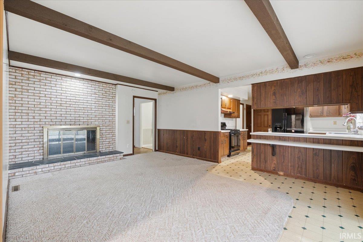 Image 2: Kitchen with wood walls, wainscoting, a peninsula, light countertops, and a brick fireplace, Kitchen
