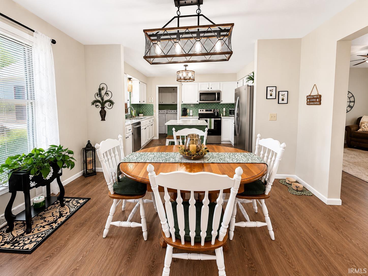 Image 2: Dining area featuring wood-finish flooring, a contemporary chandelier, and a pass-through to the kitchen, Dining Area Image 2: Dining area featuring wood-finish flooring, a contemporary chandelier, and a pass-through to the kitchen, Dining Area