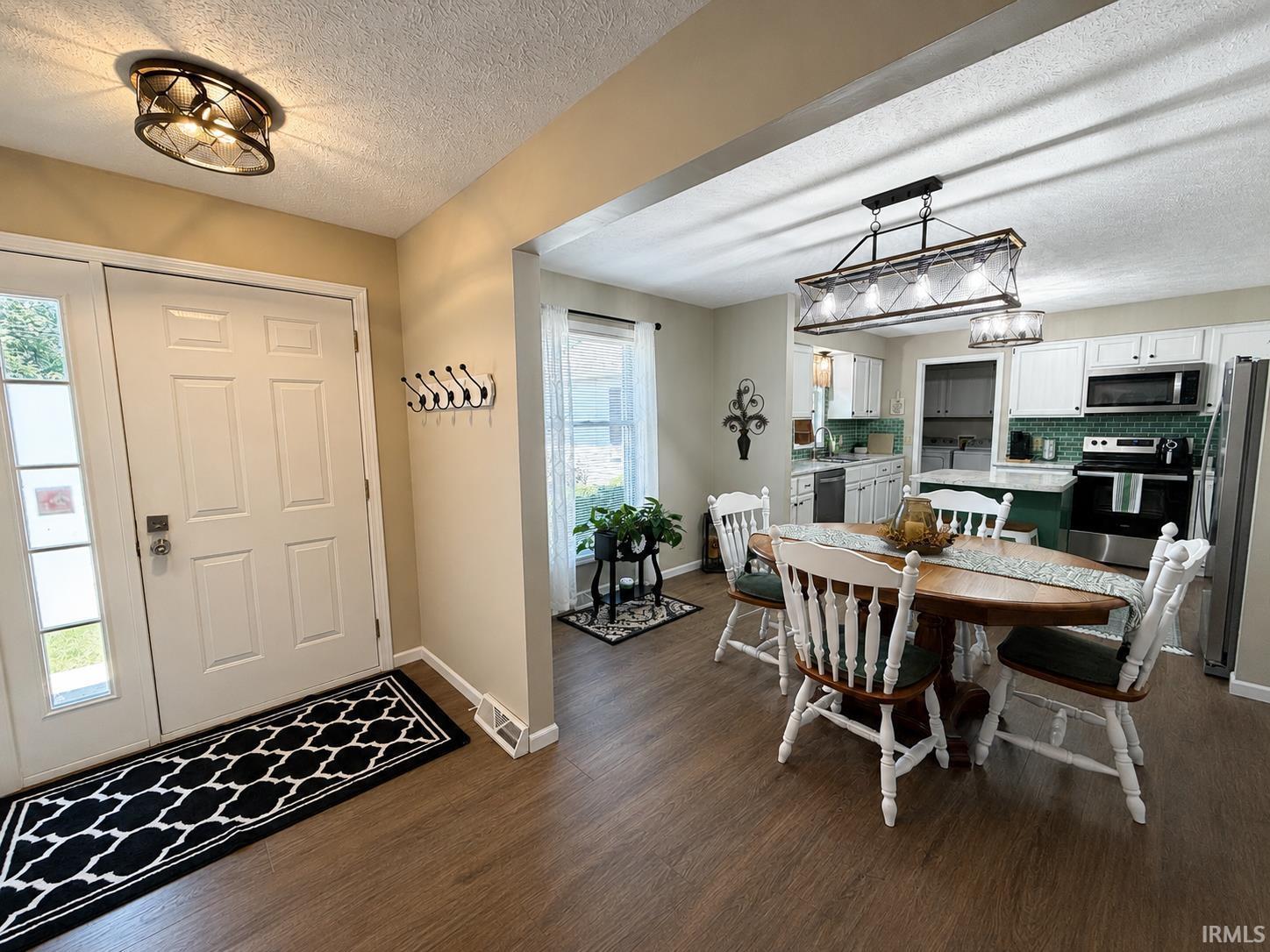 Image 3: Open-concept living space with wood-finish flooring extending from the entryway, Entrance Foyer Image 3: Open-concept living space with wood-finish flooring extending from the entryway, Entrance Foyer