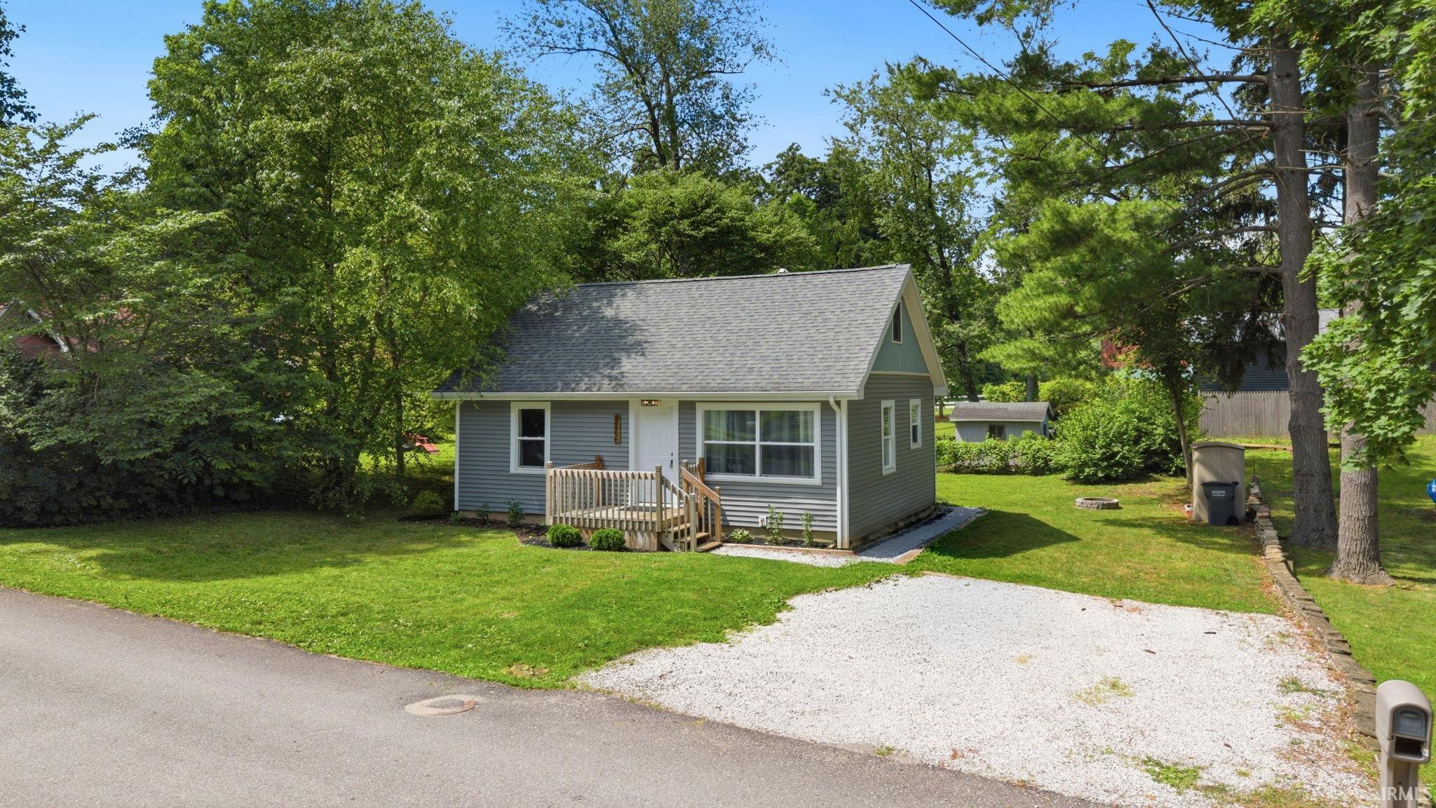 Image 2: Gray-sided residence featuring a gabled roof and a front wood deck, Front Of Structure