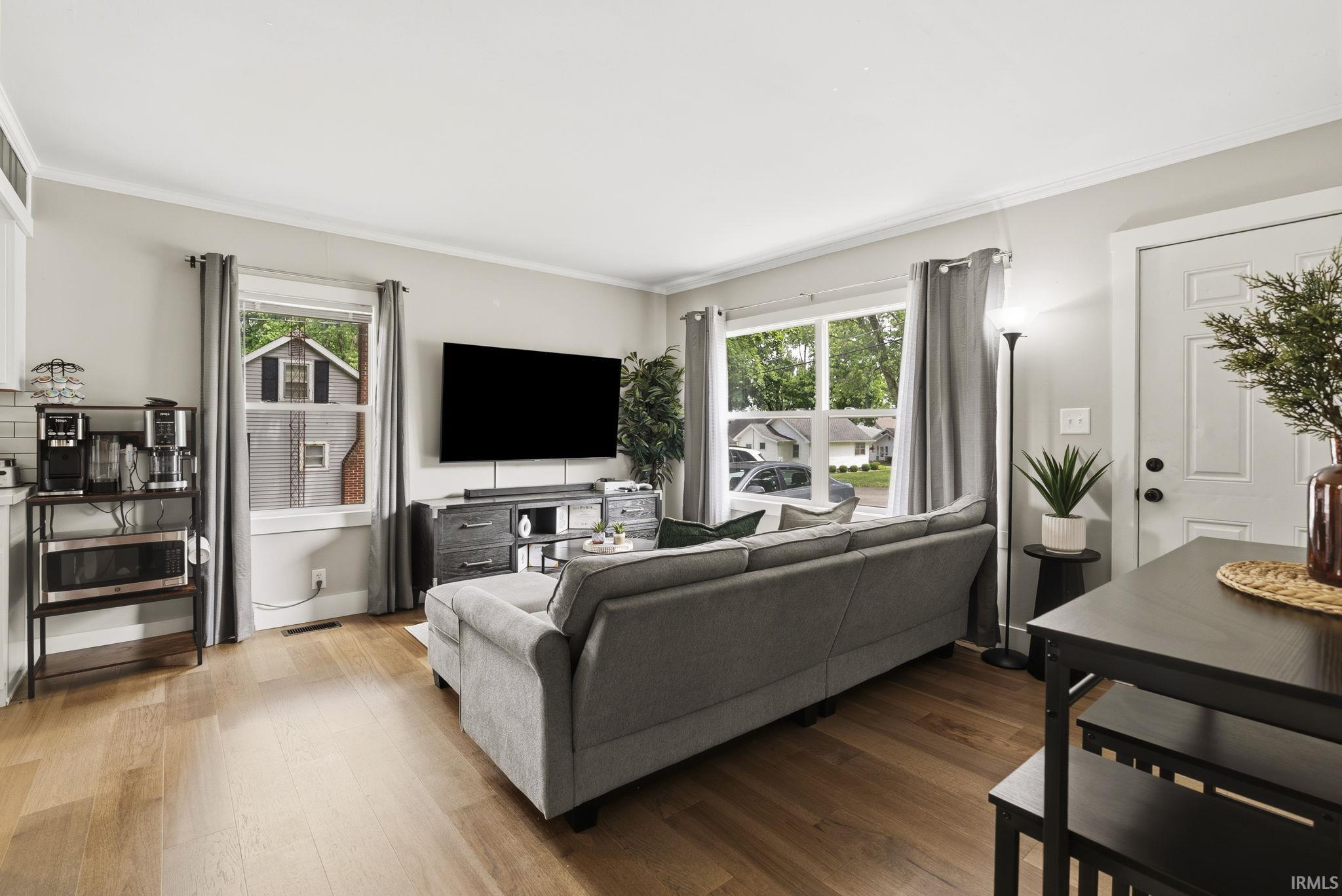 Image 3: Bright living area featuring wood-finish flooring, white trim, and multiple large windows, Living Room